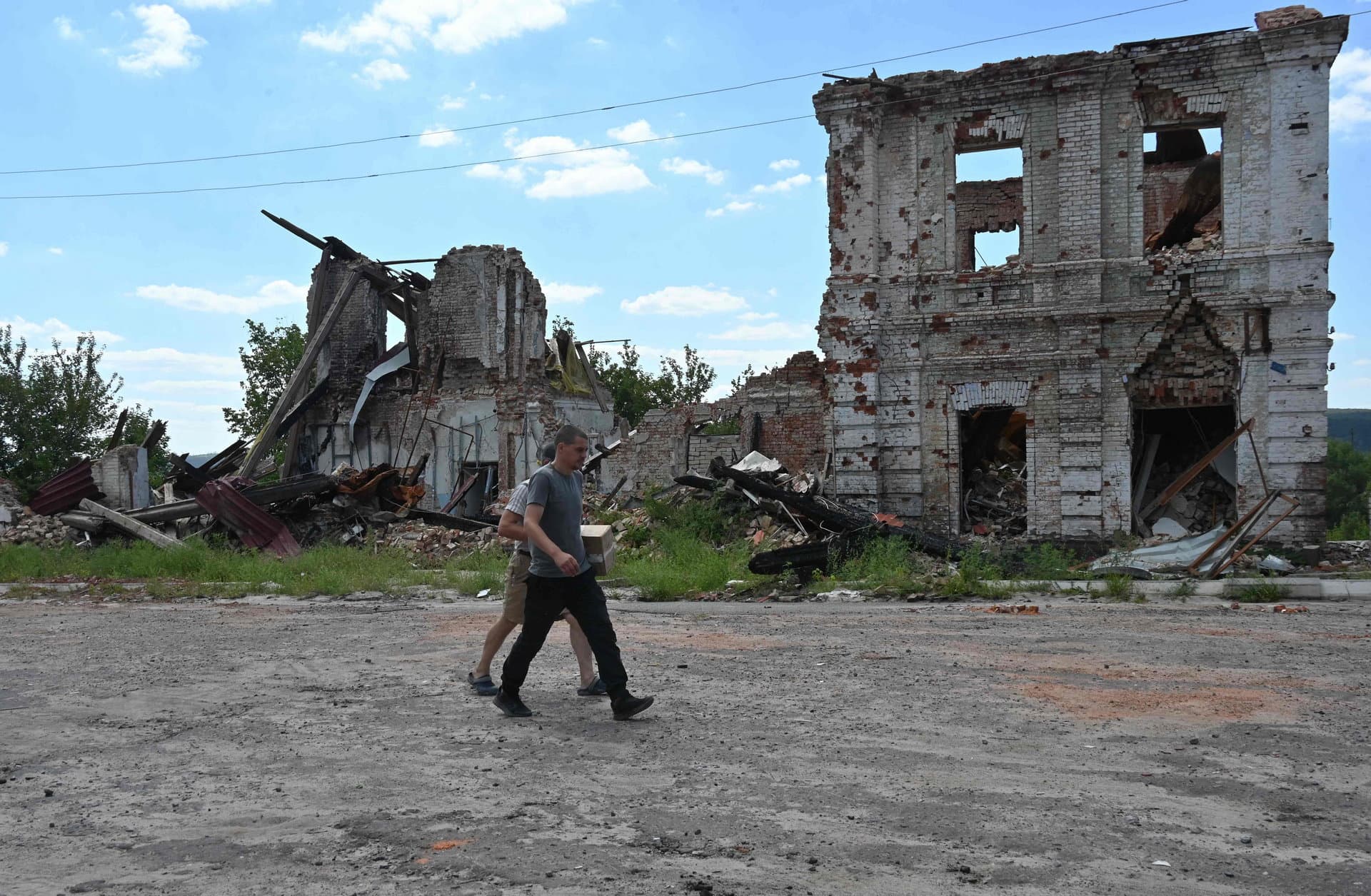 Local residents walk past a destoyed building in the town of Kupiansk