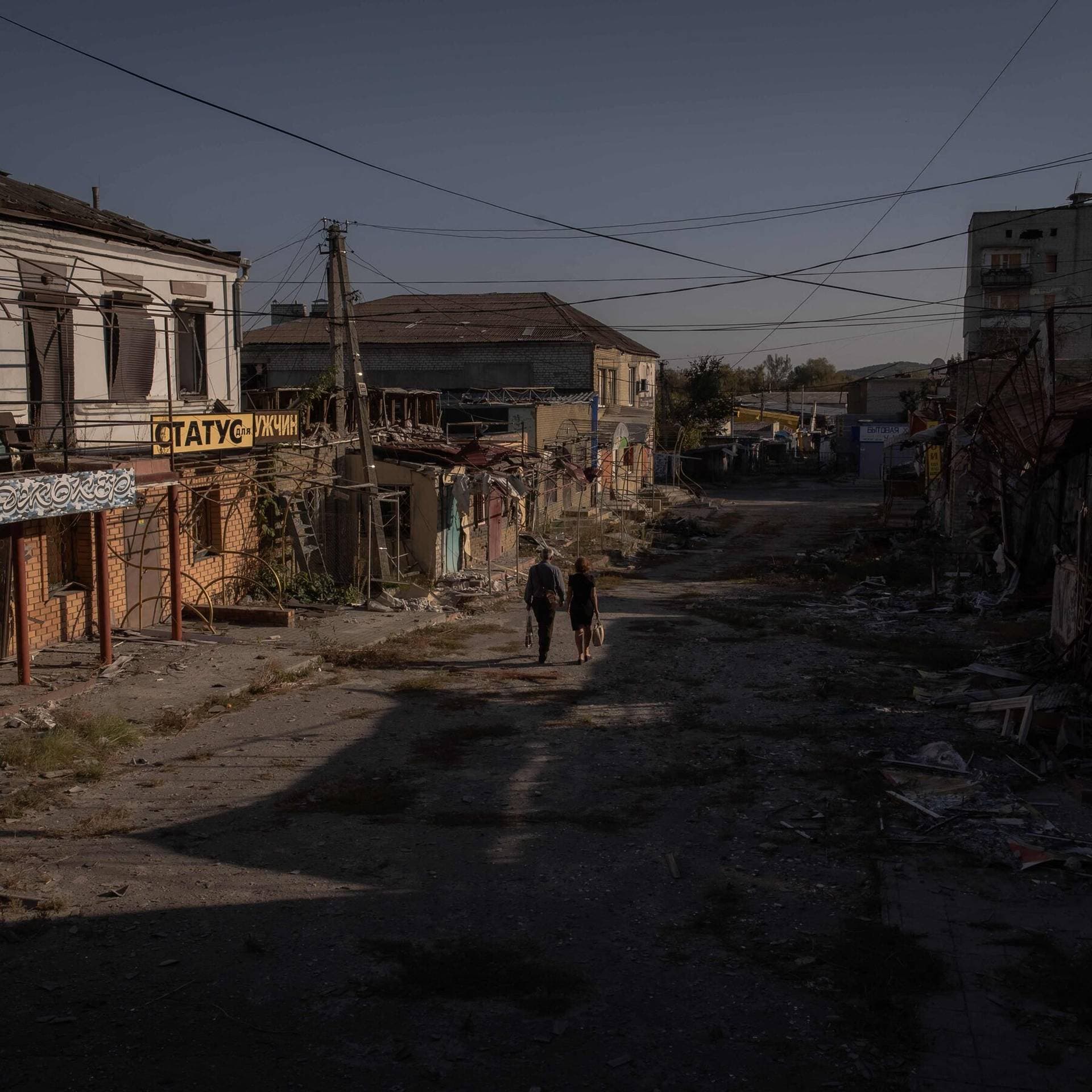 Local residents walk past damaged shops and buildings in Kupiansk
