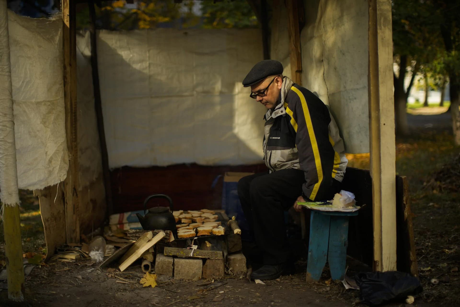 Anton Sevrukov toasts bread over fire in a makeshift stove in Kivsharivka