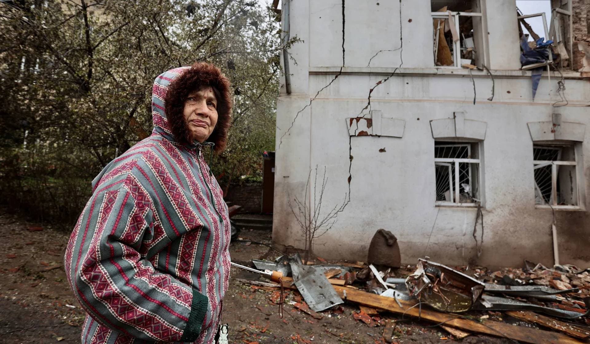 A local resident stands next to a museum building, heavily damaged by a Russian missile strike in Kupiansk