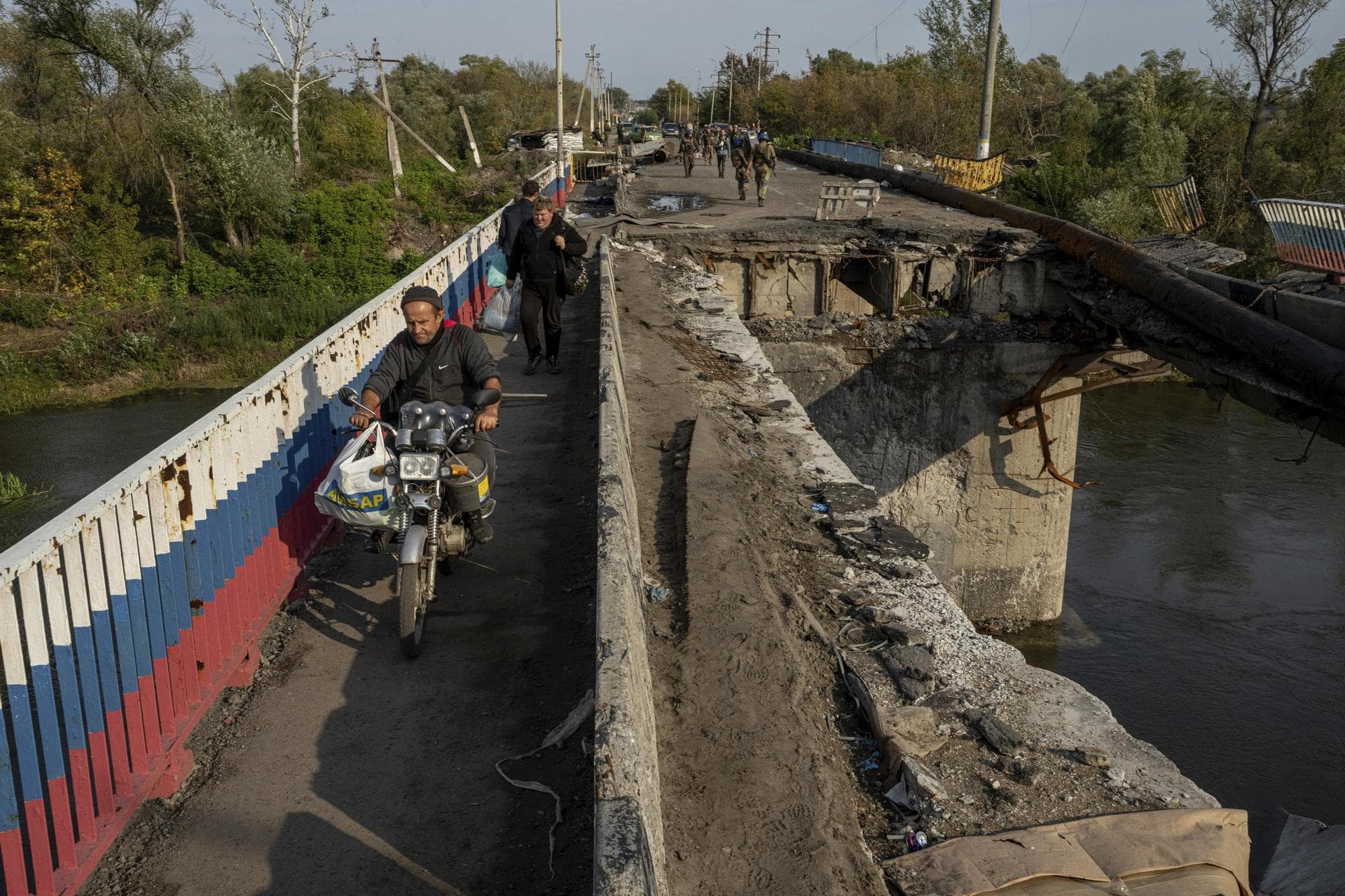 A man drives by motorbike on a destroyed bridge across Oskil river during evacuation in recently liberated town Kupiansk