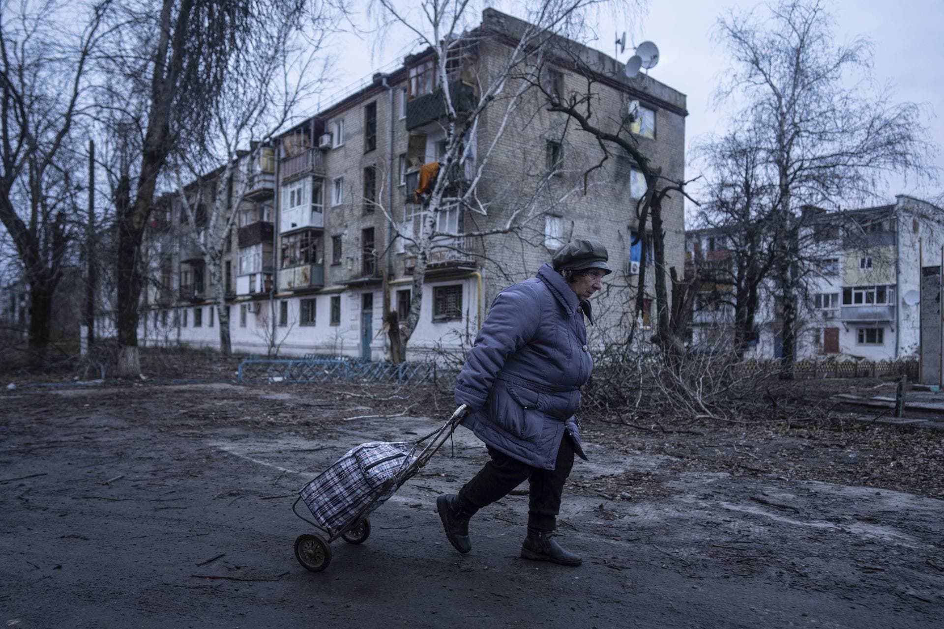 A local woman walks to the distribution point of humanitarian aid in front of housing that was damaged by Russian shelling in Kupyansk