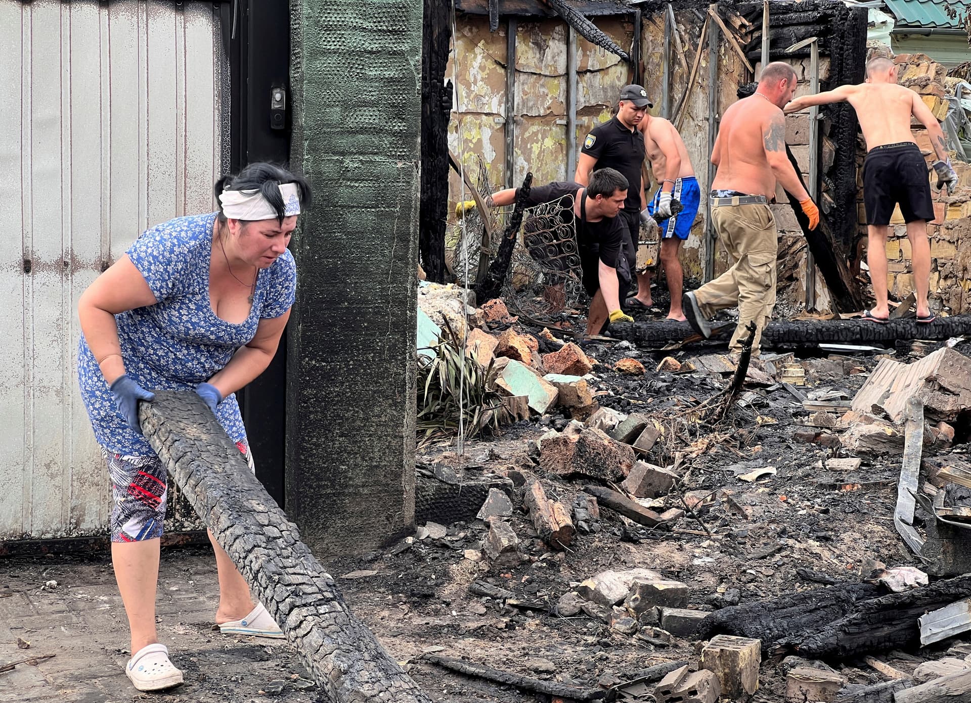 Local residents remove debris from buildings damaged by a Russian missile strike in the village of Tarasivka 