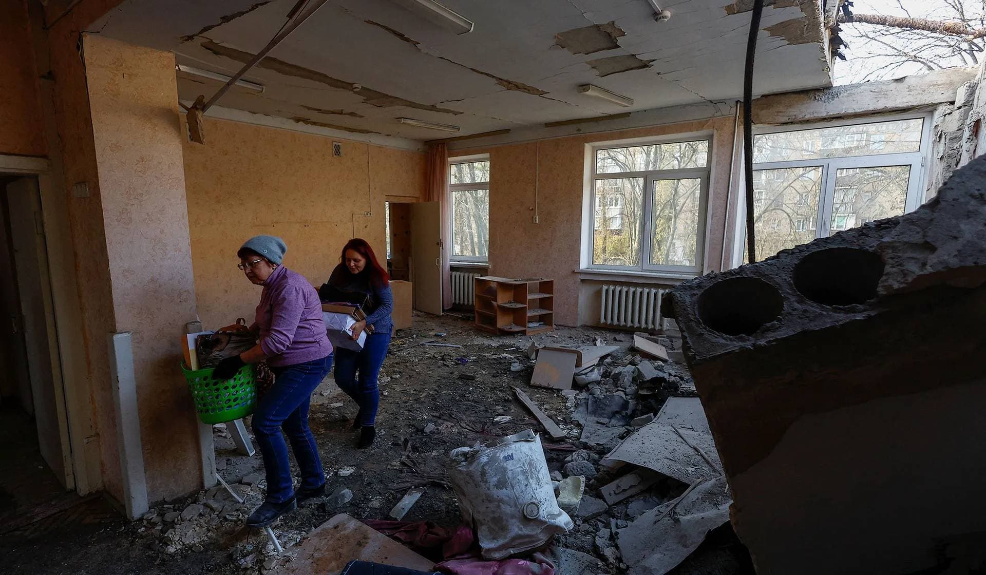 Employees carry items inside a building of a kindergarten damaged during Russian drone strikes in Kyiv