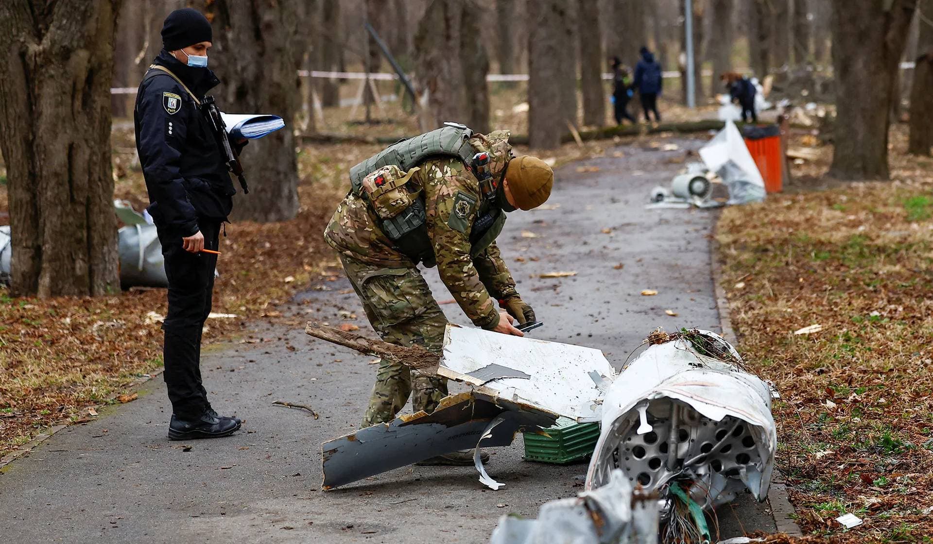 Police officers inspect a part of a Russian Kh-55 cruise missile intercepted during a missile strike in a park in Kyiv