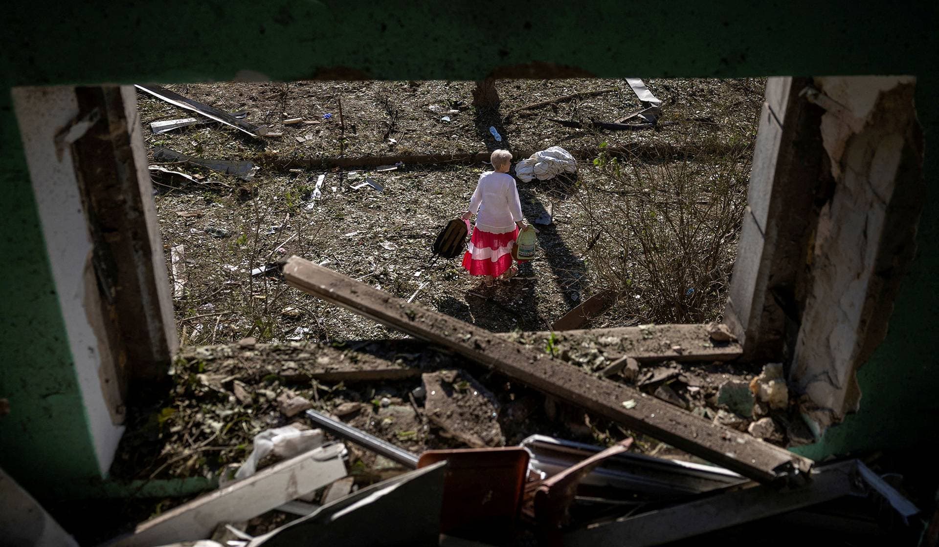 A woman carries belongings from her apartment building after it was damaged during a night of Russian missile and drone strikes in Kyiv