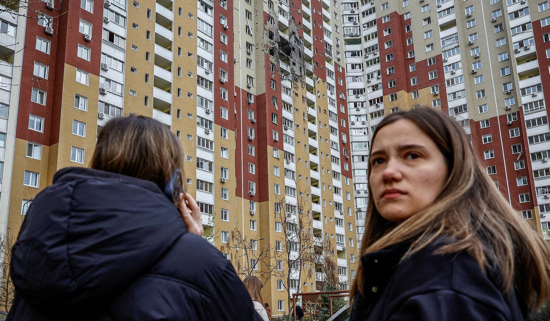 Residents stand near a residential building damaged during Russian drone strike in Kyiv