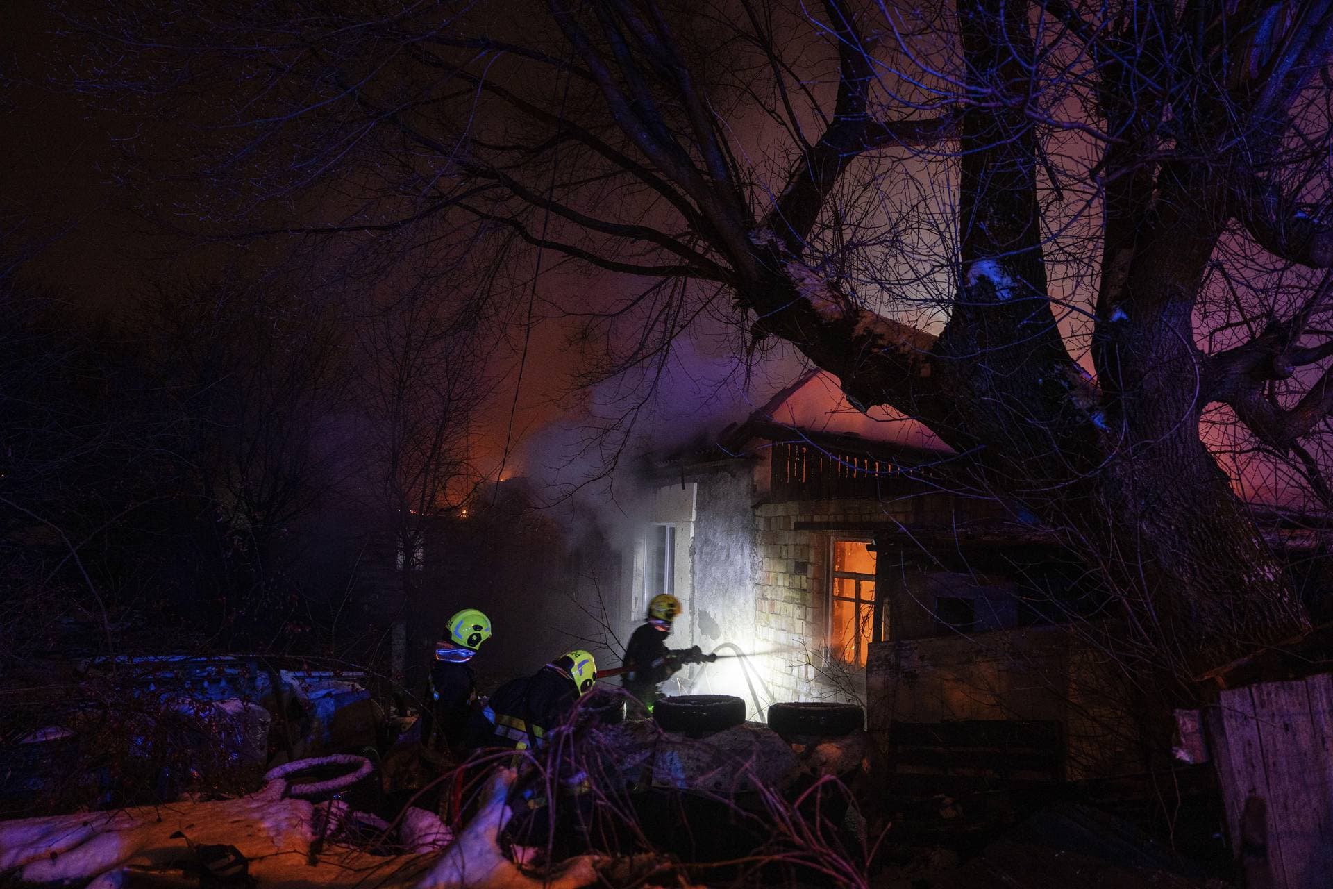 Rescue workers extinguish a fire at a residential house after a Russian rocket attack in Kyiv