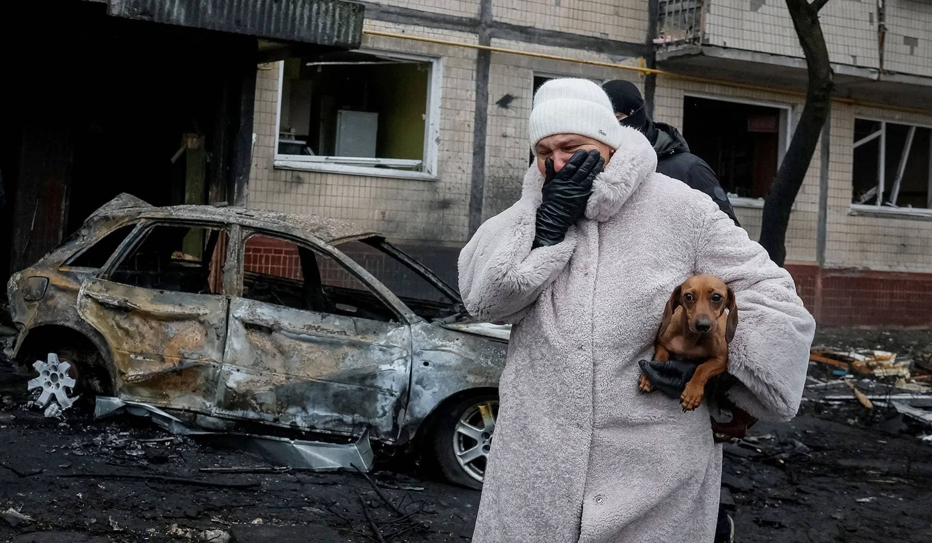 A local resident leaves her apartment building damaged during a Russian missile strike in Kyiv