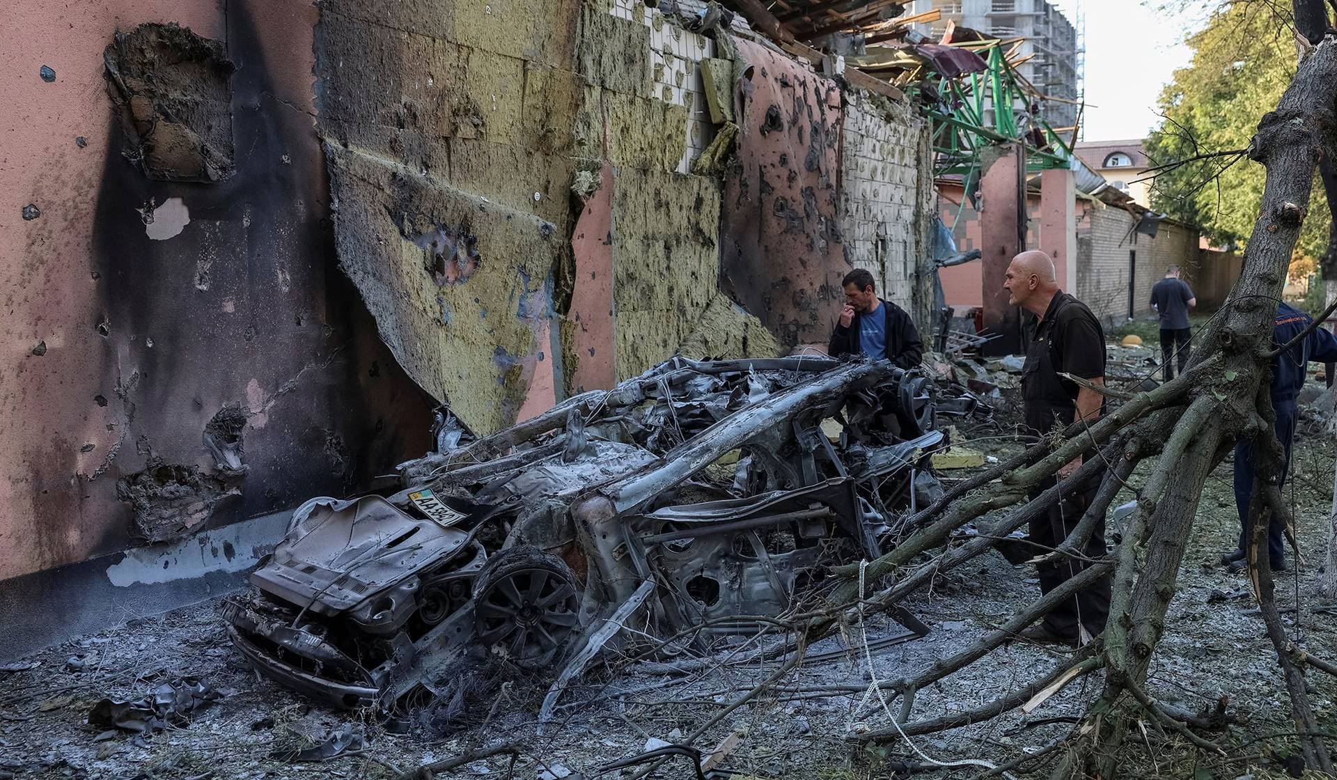 Residents look at a burned car at a site of a Russian missile strike in Kyiv Region