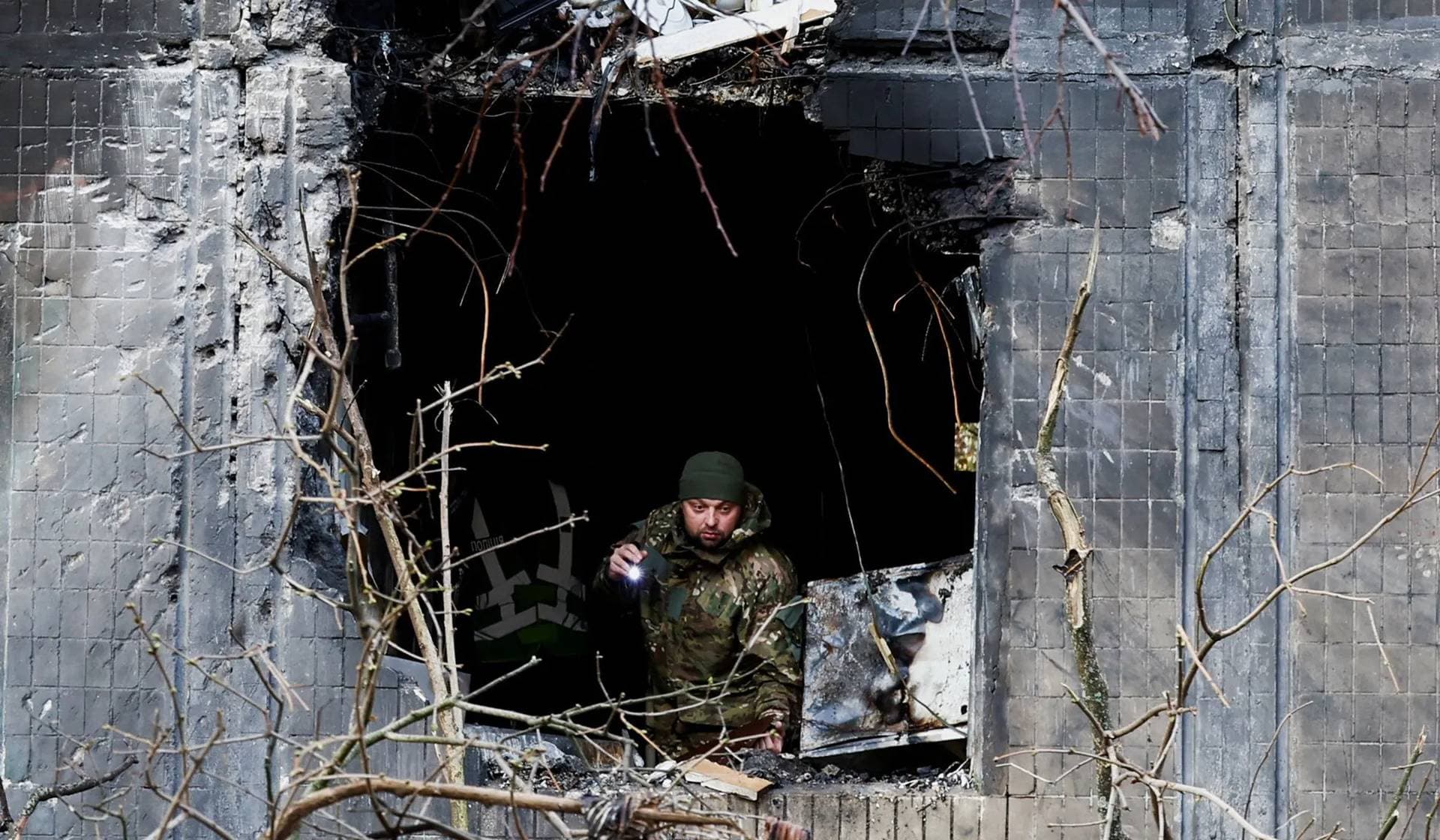An investigator looks through the window of an apartment building damaged during an overnight Russian drone and missile strike in Kyiv