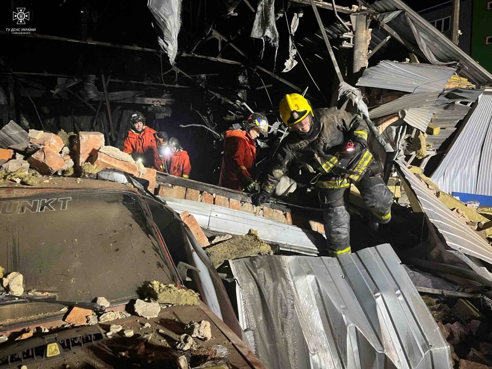 Firefighters work at a site of a warehouse heavily damaged during a Russian drone strike in Kyiv region
