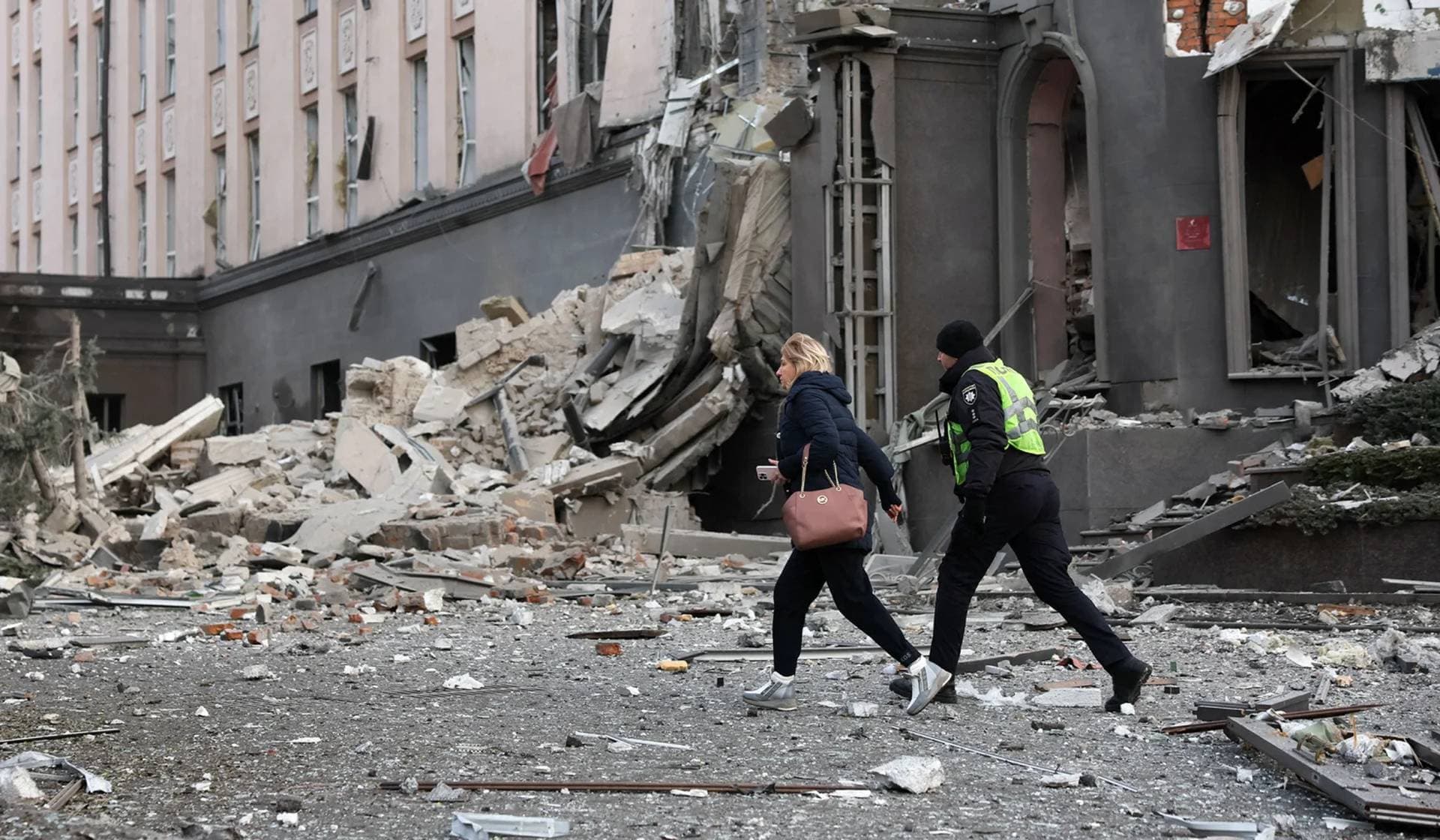 A woman and police officer walk at the site of a building damaged during a Russian missile strike in Kyiv