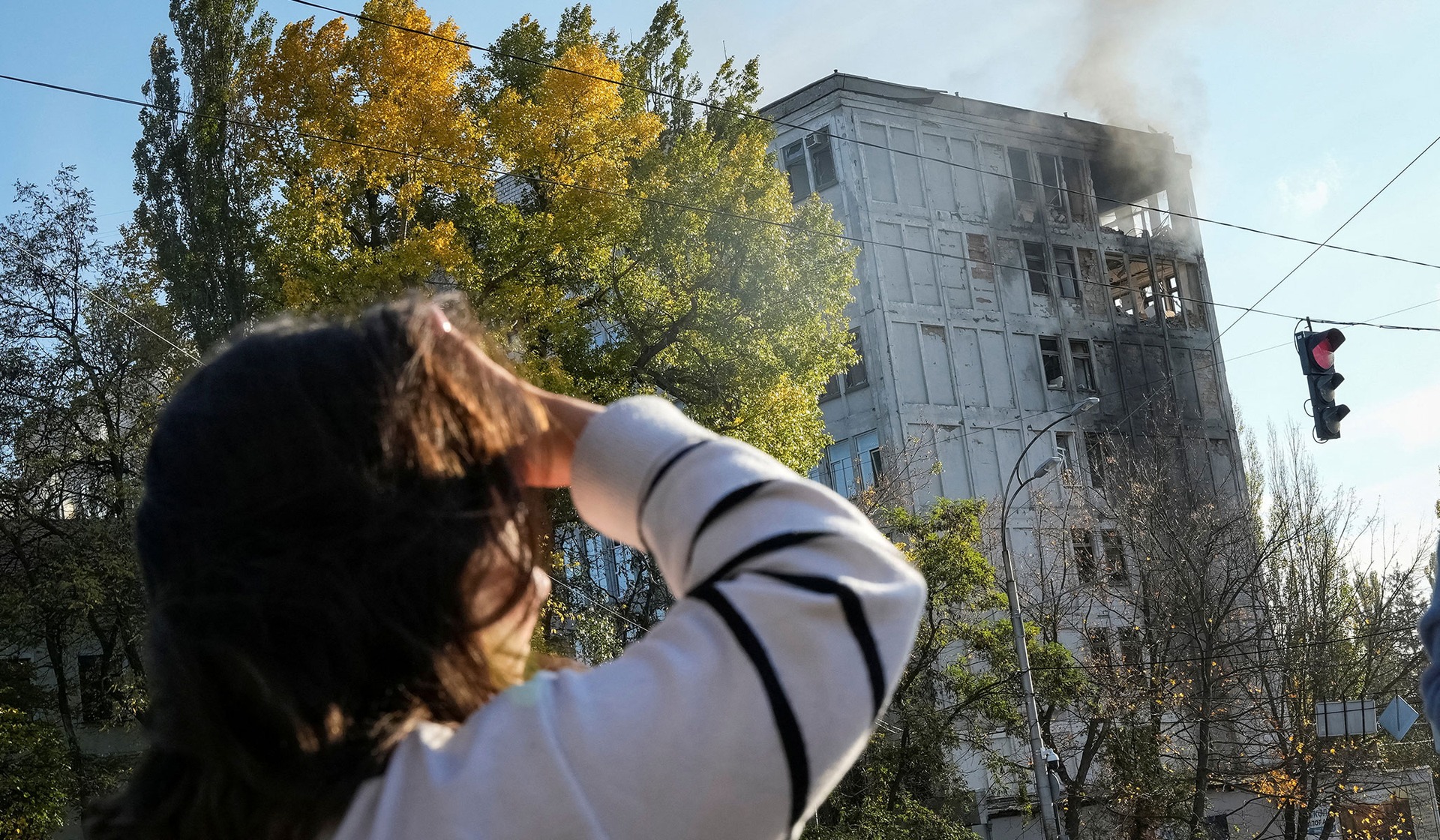 A woman looks at an office building damaged during a Russian drone strike in Kyiv
