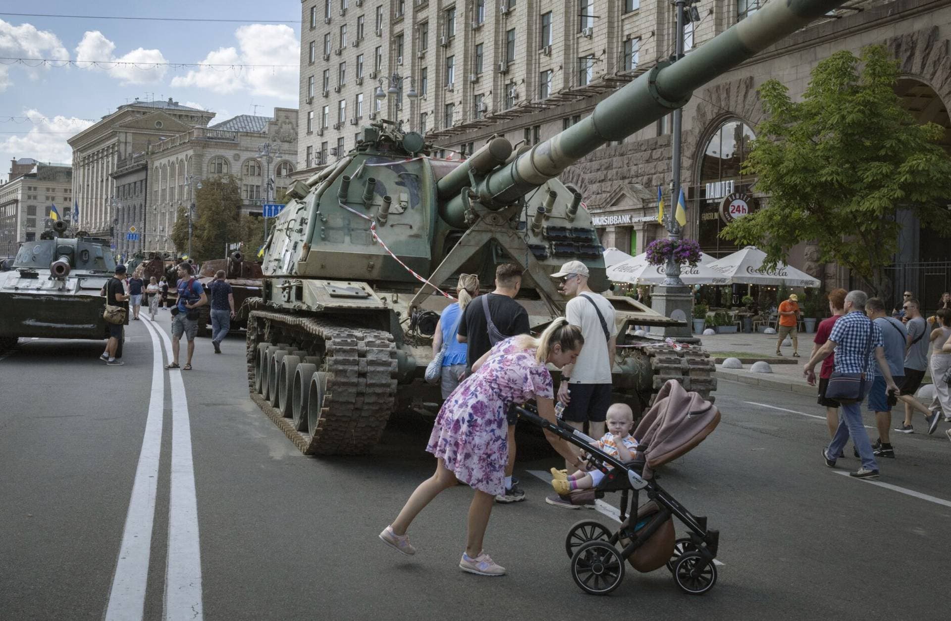 People look at a large column of burnt out and captured Russian tanks and infantry carriers in Kyiv