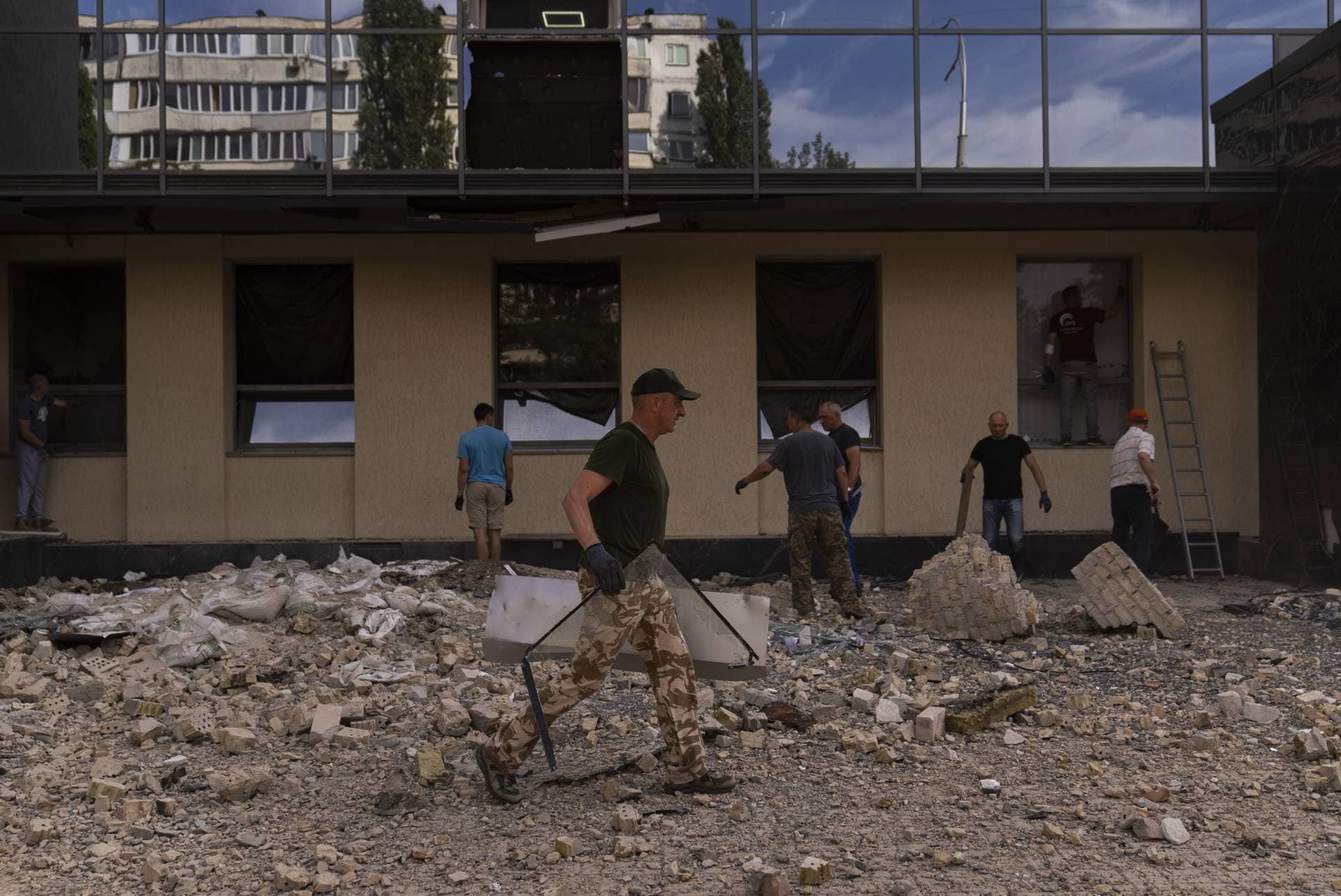 People clean up debris outside a damaged government building in Kyiv