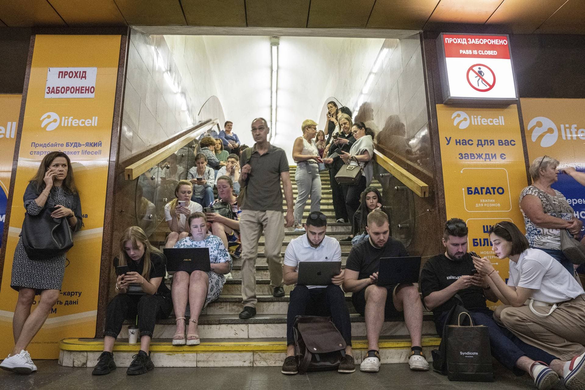 People working on their laptops while they take cover at metro station during a Russian rocket attack in Kyiv
