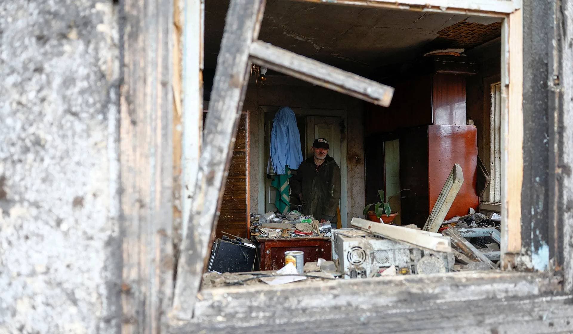 A local resident Andrei looks out of a window of his house, heavily damaged by a Russian missile strike, in Kyiv