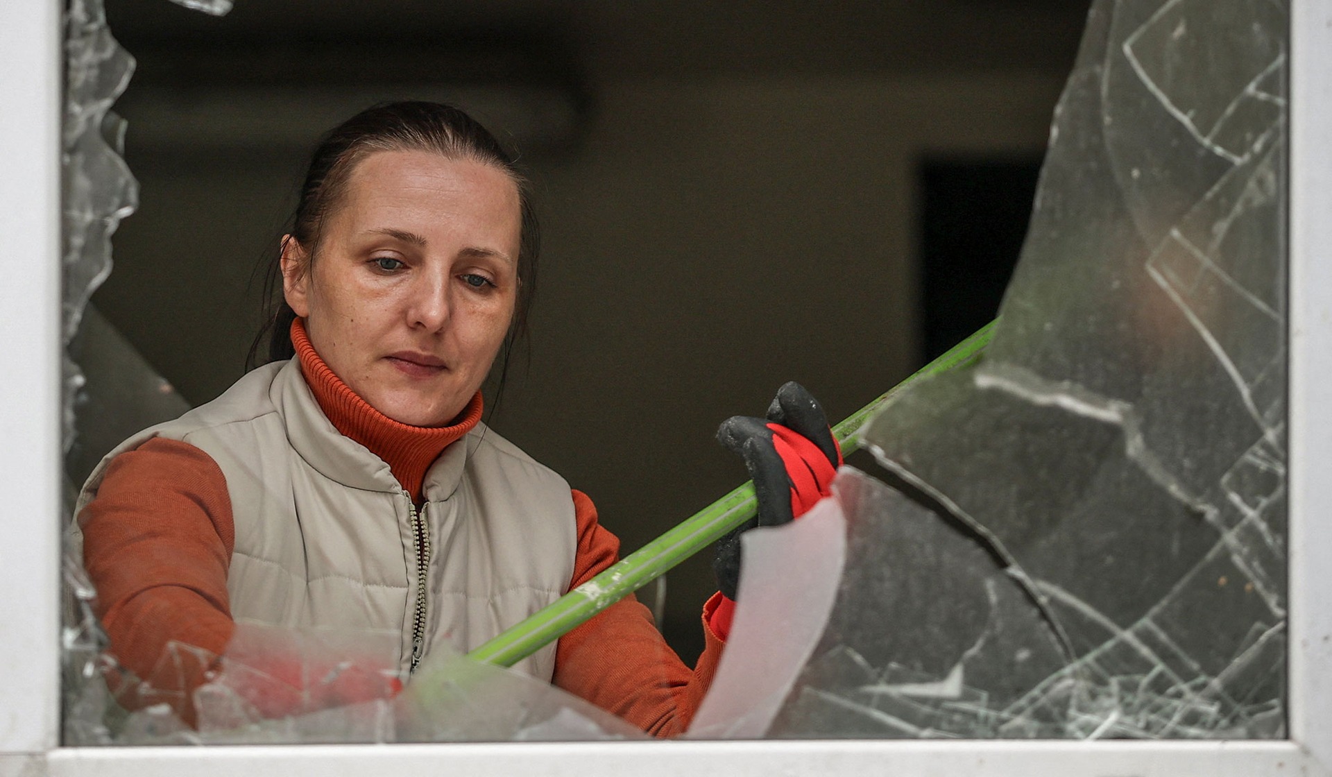 A primary health care center employee cleans up glass from broken windows at a site of a Russian missile strike in Kyiv