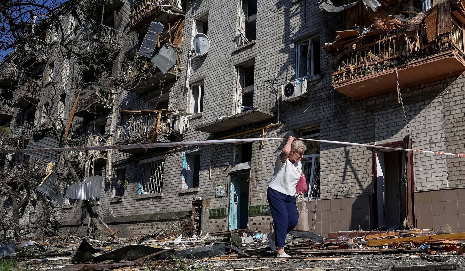 A resident walks near an apartment building damaged during a Russian missile and drone strike in Kyiv