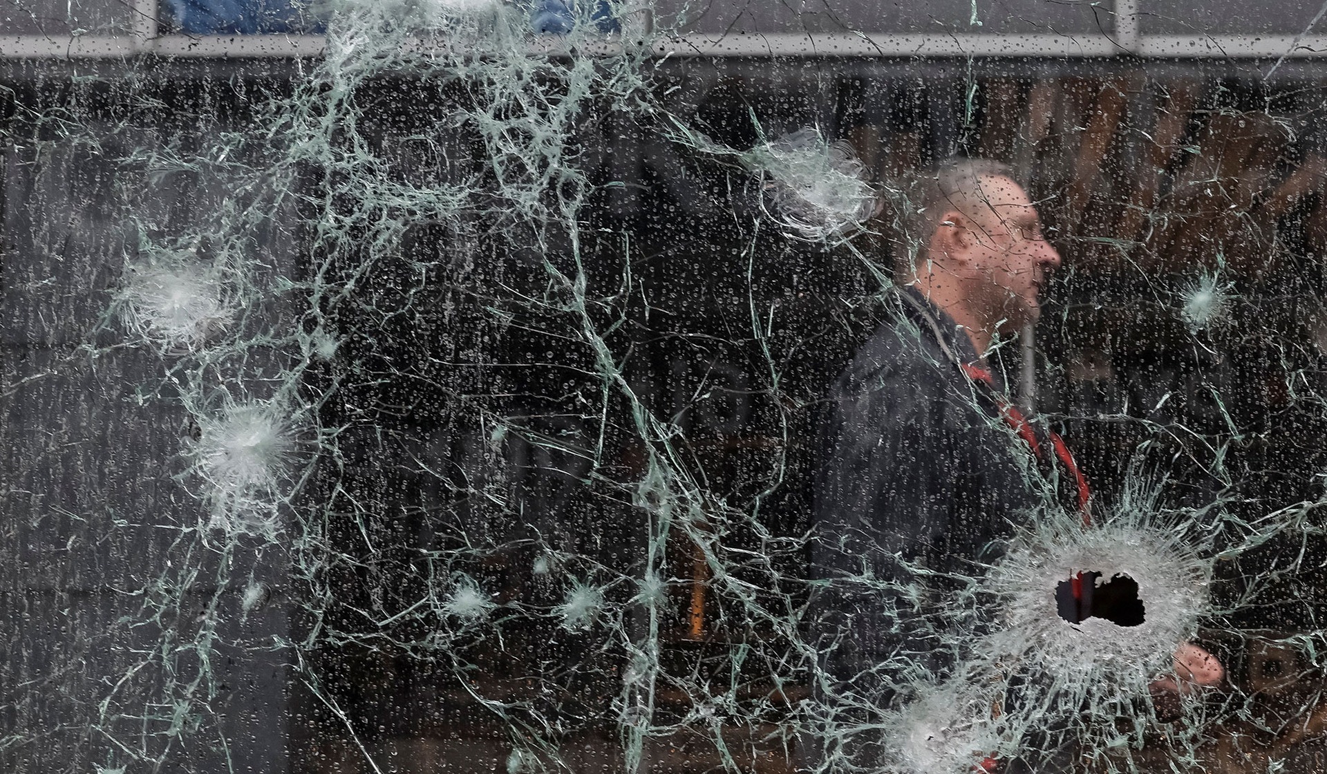 A man walks near a glass railing with shrapnel holes at the site of a shopping mall in Kyiv