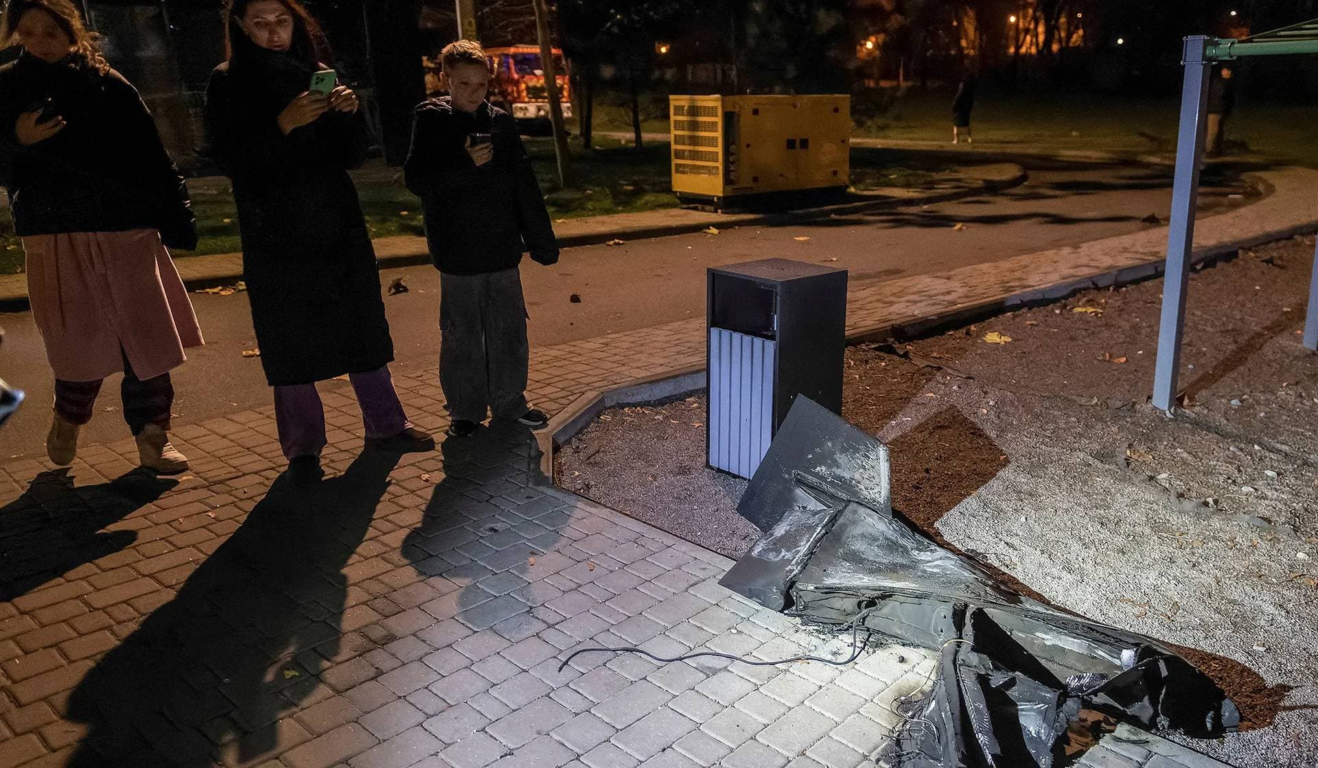 Residents take pictures of a part Russian drone after a missile and drone strike in Kyiv