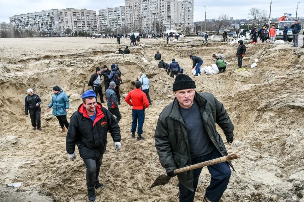 Locals fill sandbags to use it to strengthen roadblocks on the roads leading to Kyiv