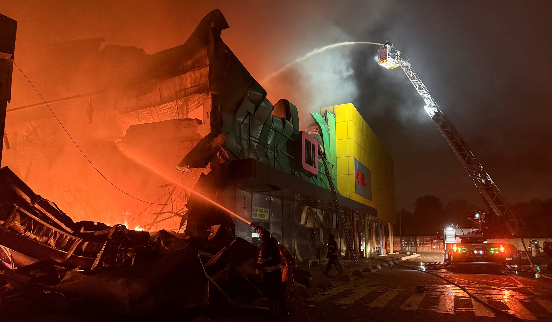 Firefighters work at the site of a shopping center hit by a Russian missile attack in Kyiv