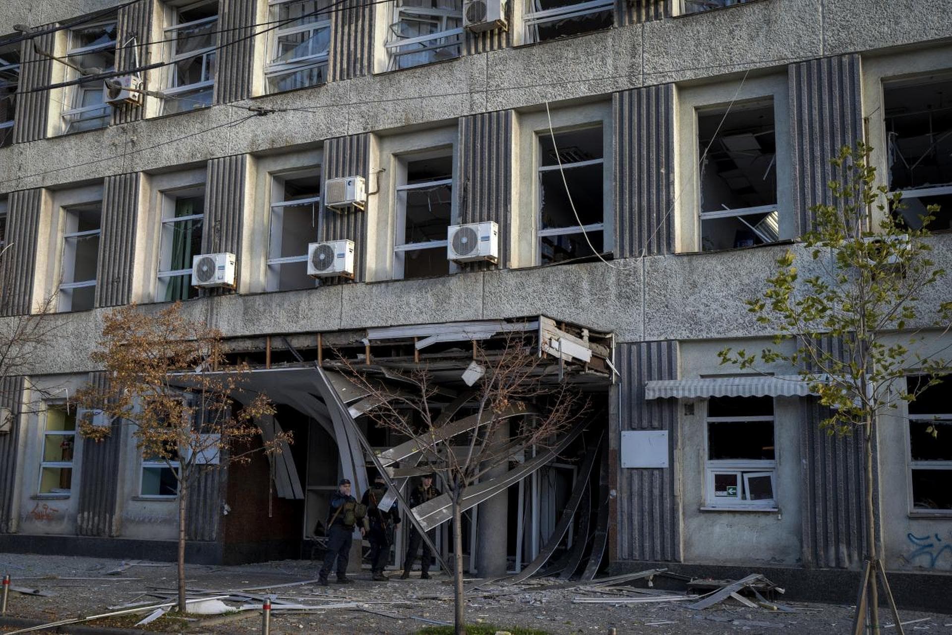 Police officers stand near a damaged building after a Russian attack in Kyiv