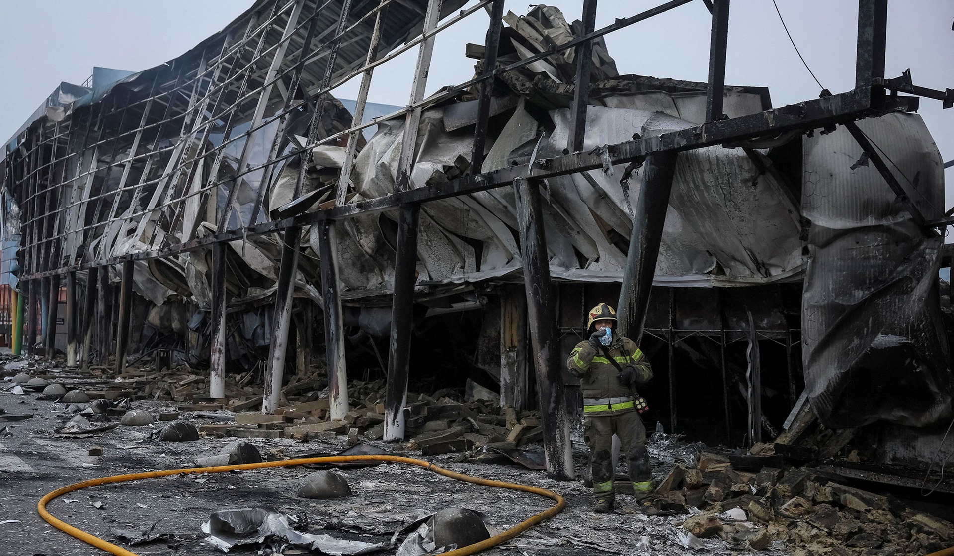 A rescuer takes a break and drinks water as he works at the site of a shopping center hit by a Russian missile attack in Kyiv