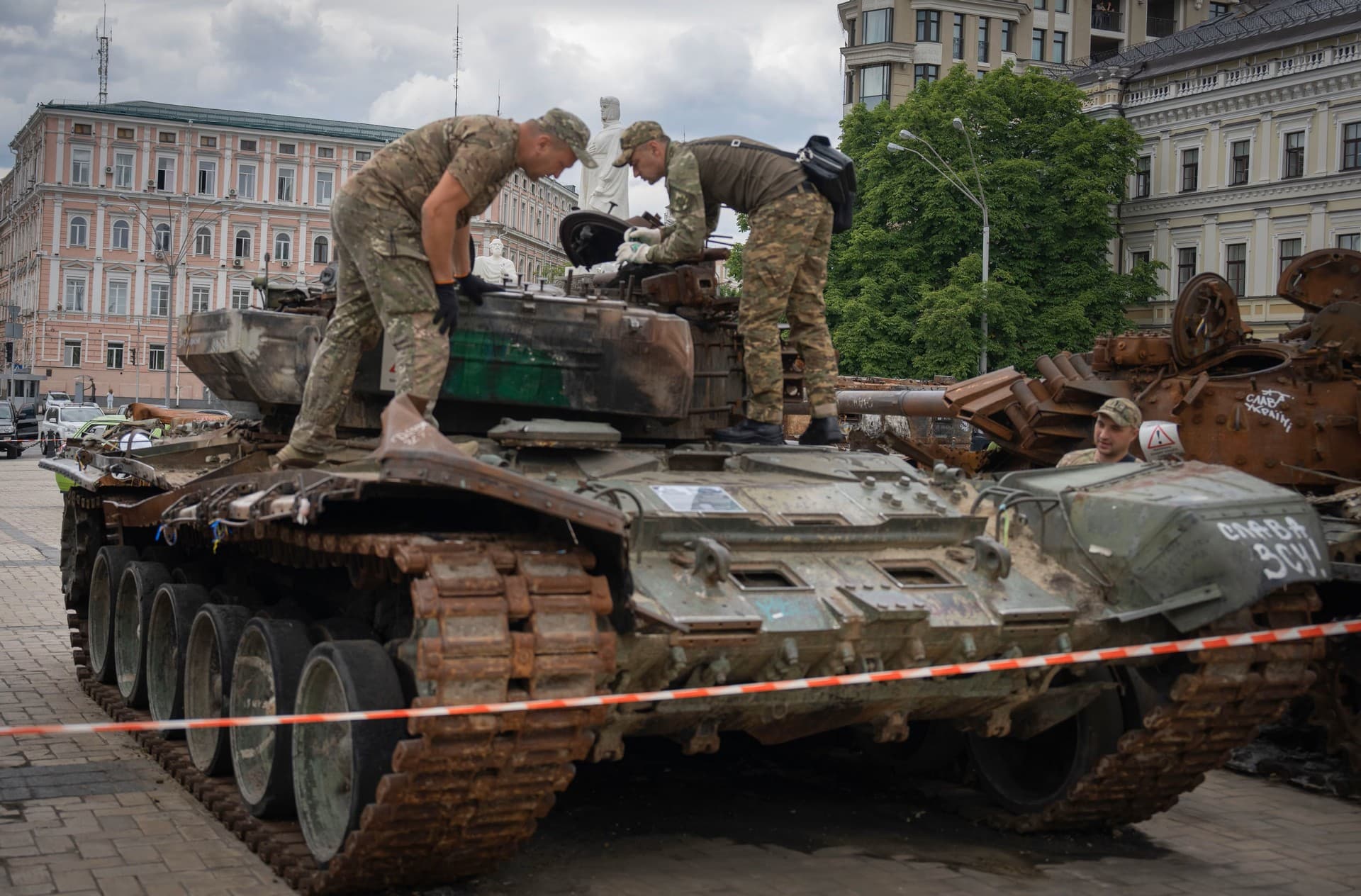 Sappers inspect a damaged Russian tank installed as a symbol of war in central Kyiv