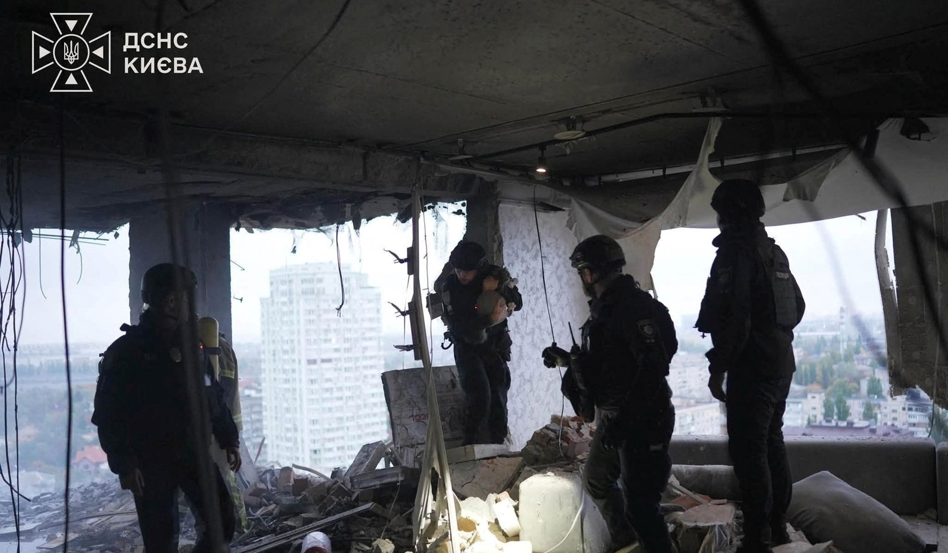 Police officers and a firefighter inspect an apartment in a residential building which was hit by a Russian drone strike in Kyiv