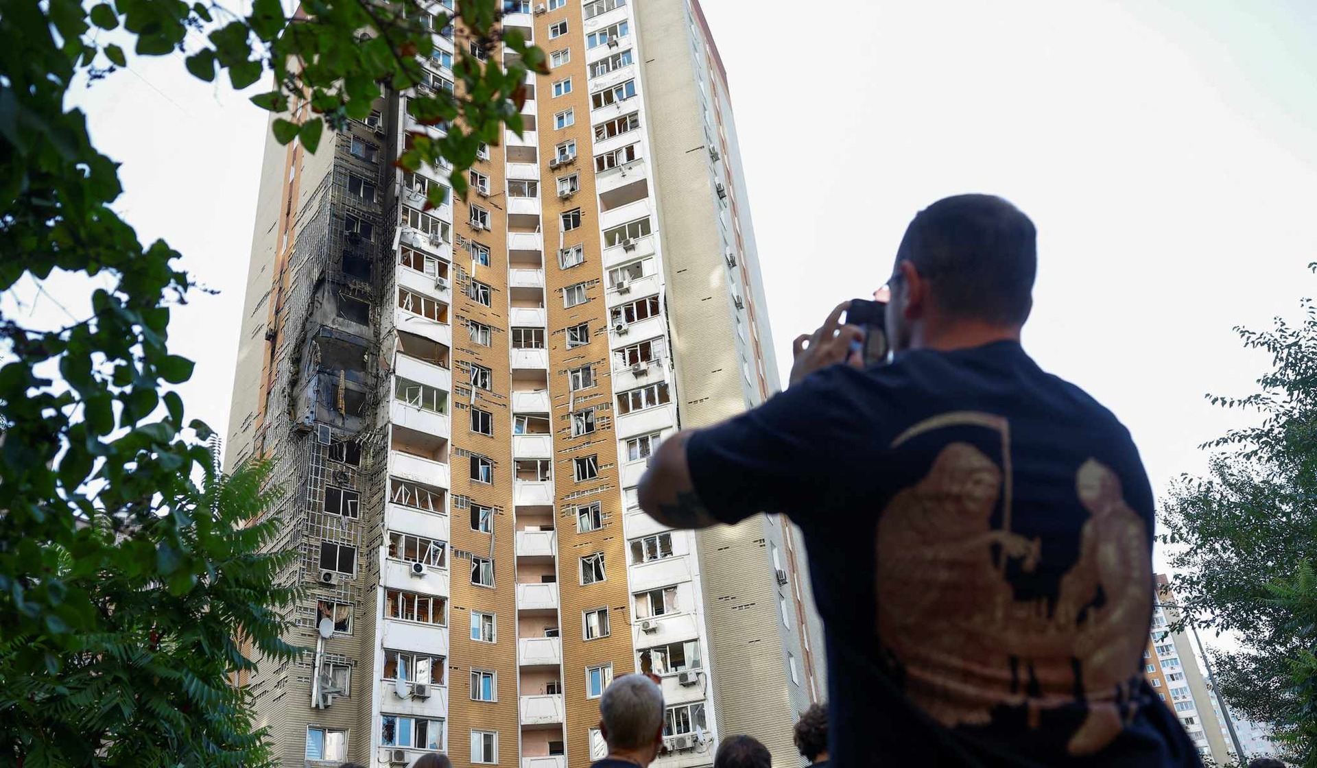 People gather outside an apartment building hit by a Russian drone strike in Kyiv