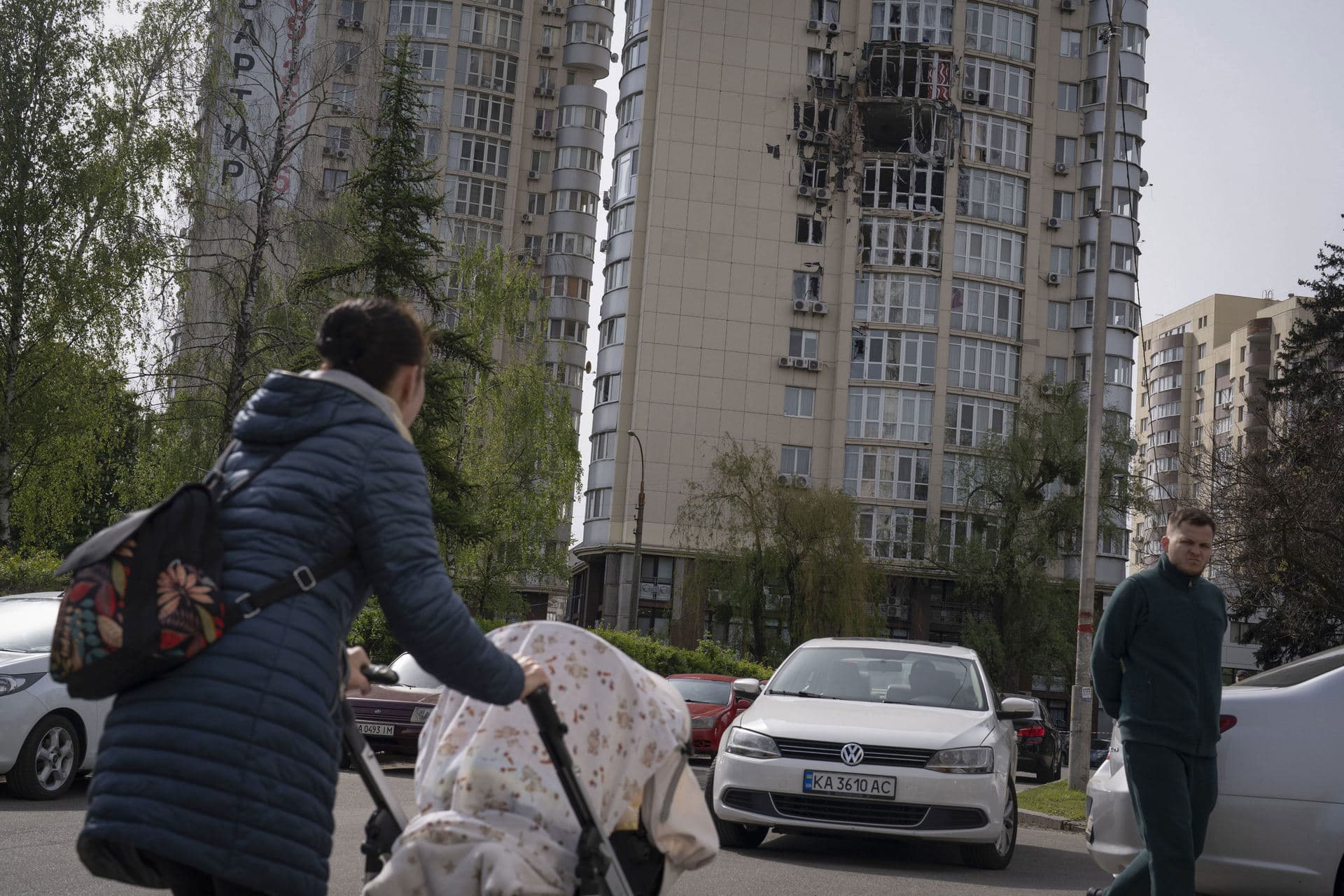 People pass by an apartment building damaged by a drone that was shot down, during a Russian overnight strike, amid Russia's attack, in Kyiv
