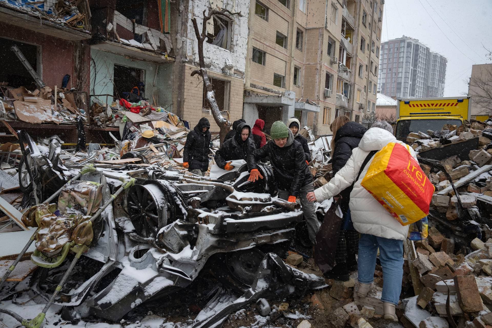 Volunteers and residents clear debris of an apartment building destroyed after Tuesday Russian attack in Kyiv