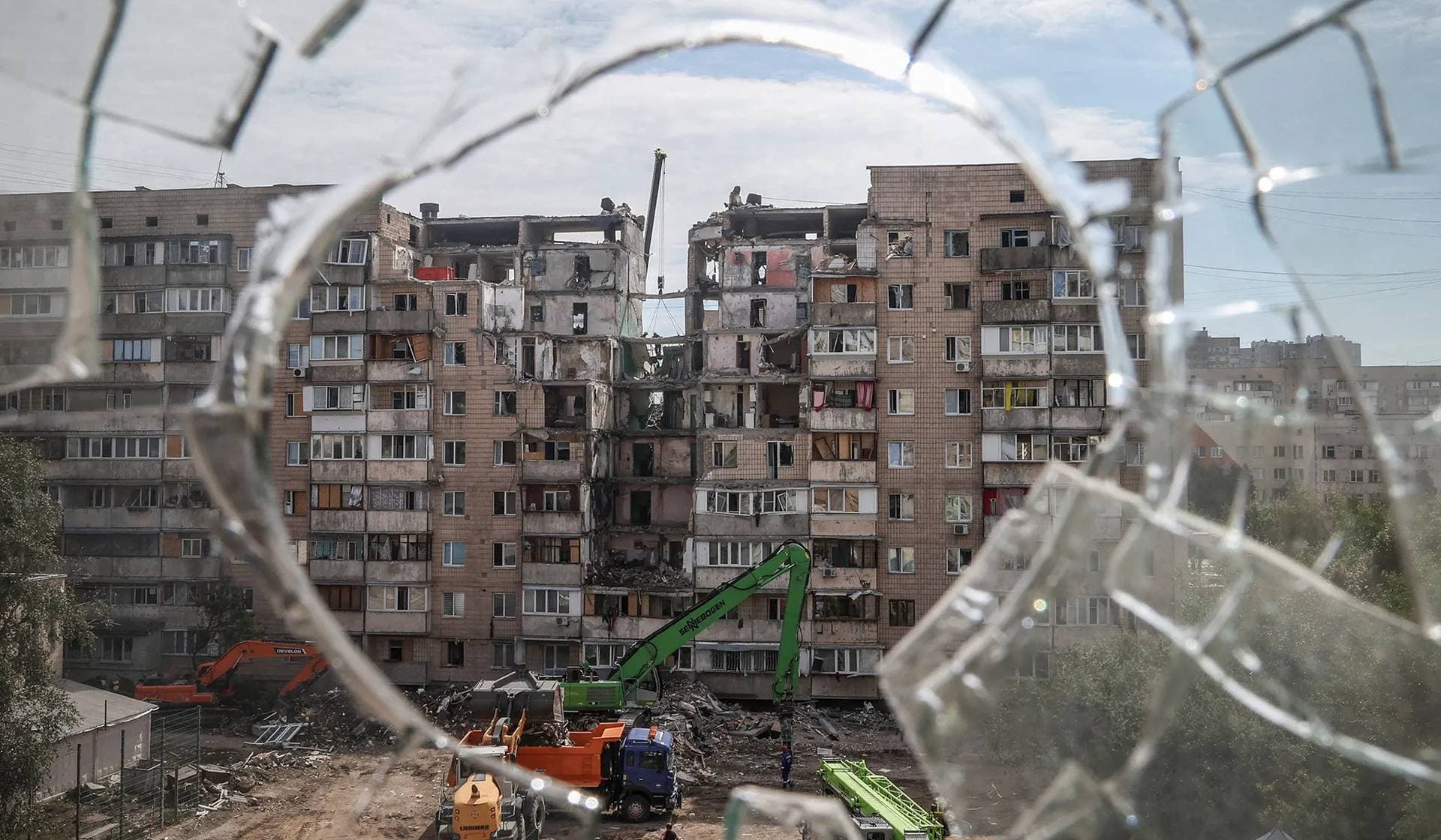 Rescuers working at a site of a Russian missile and drone strike on the previous day, during which residential building was heavily damaged, seen through broken glass, in Kyiv