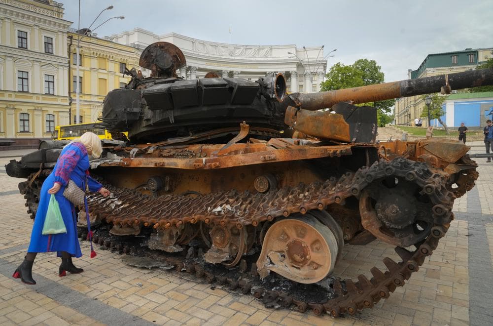 A woman looks at a destroyed Russian tank installed as a symbol of war in Kyiv