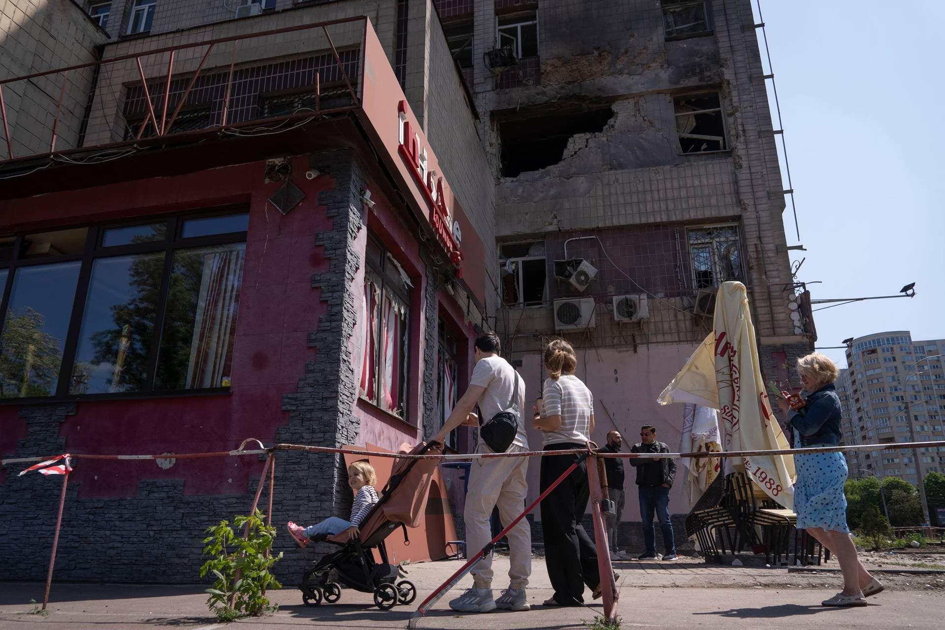 People look at an apartment building damaged by a drone during a night attack in Kyiv