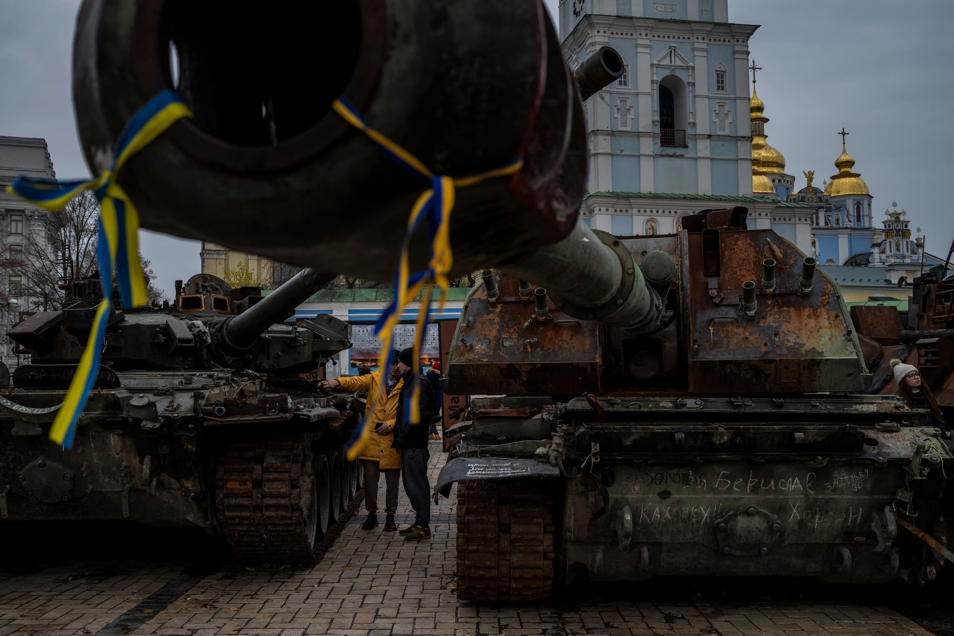 Pedestrians stand in front of a display of destroyed Russian tanks and armoured vehicles in downtown Kyiv