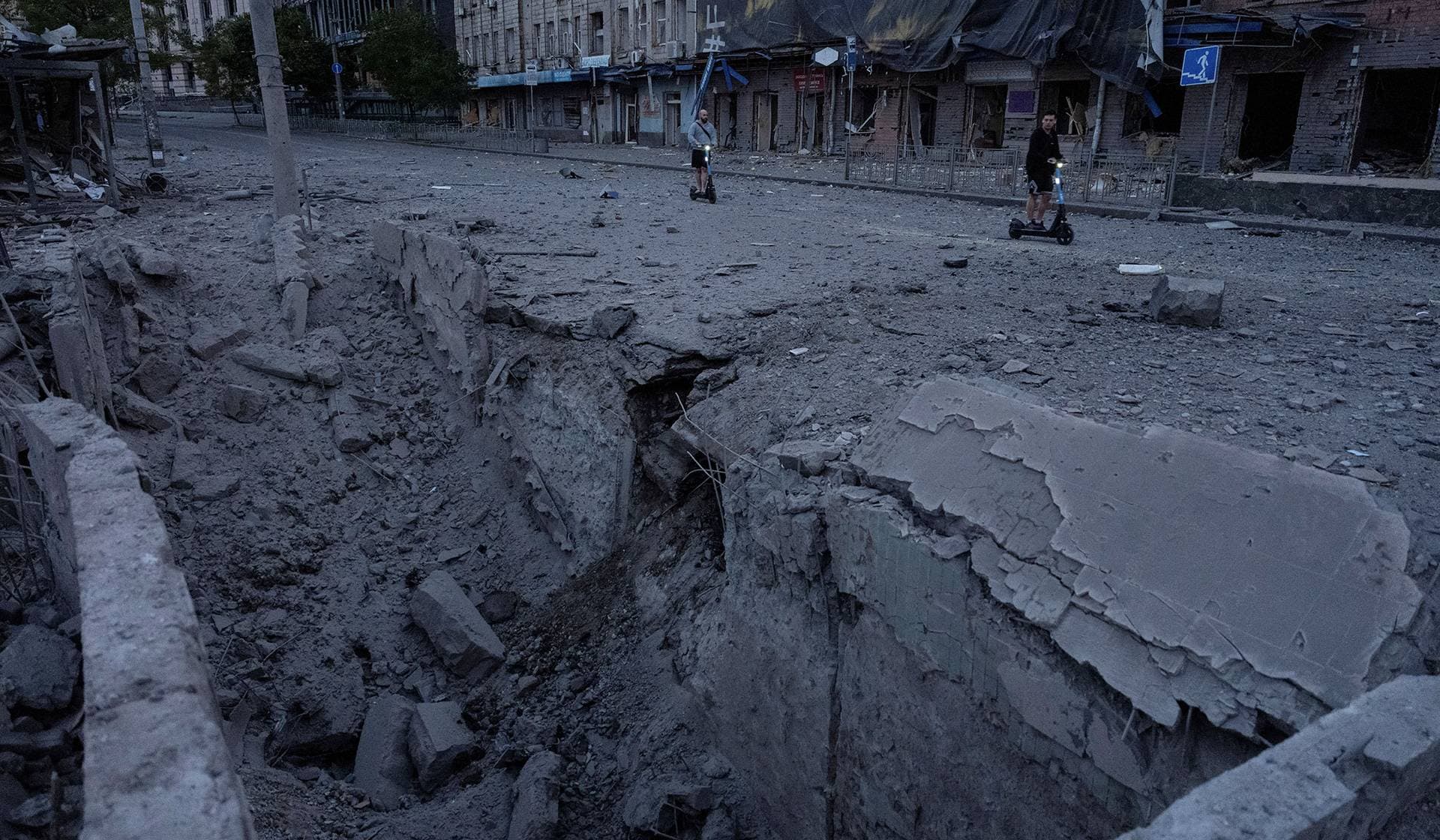Residents ride electric scooters at the site of a Russian missile strike in Kyiv