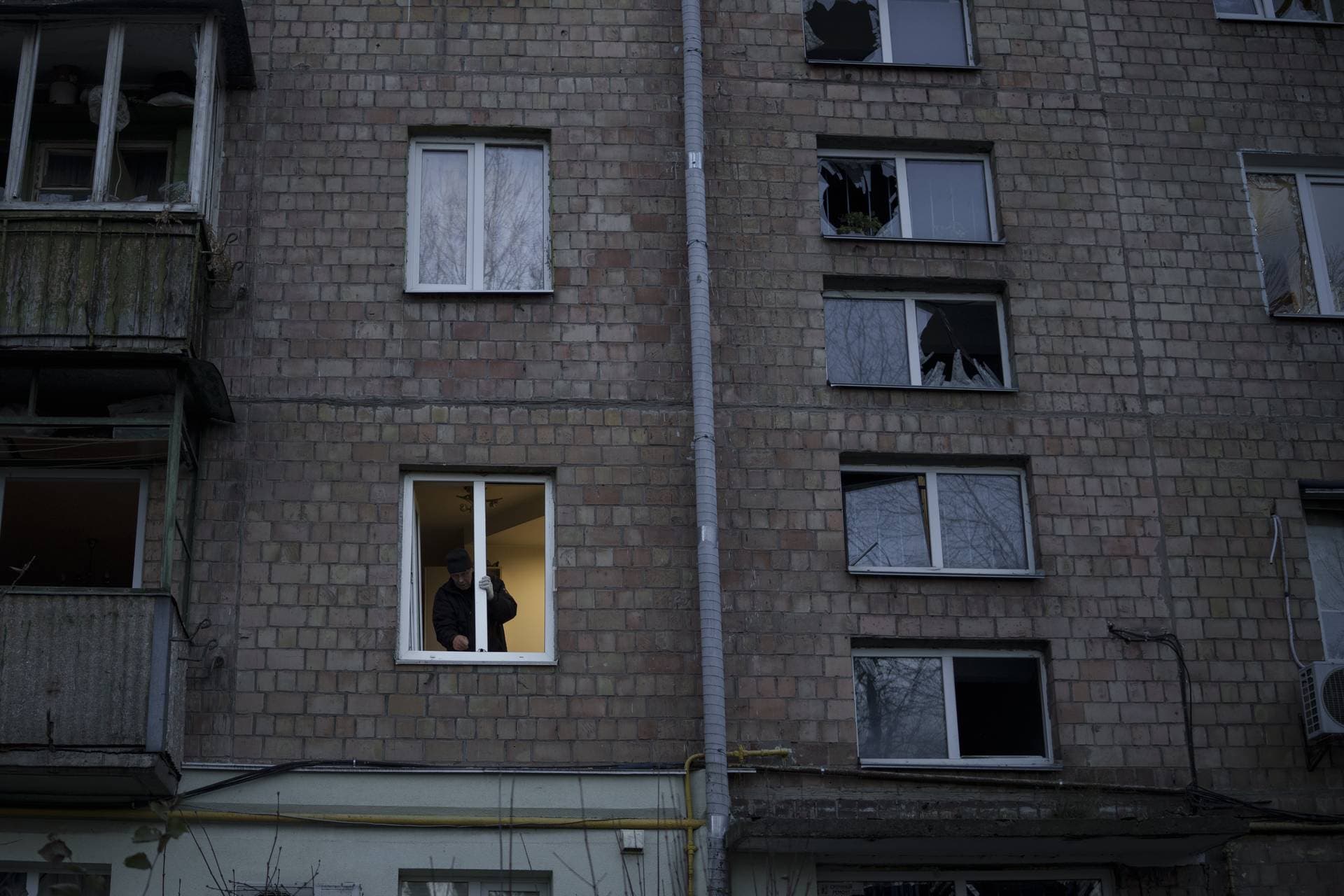 A man clear pieces of broken glass from a window after a Russian drone attack in Kyiv