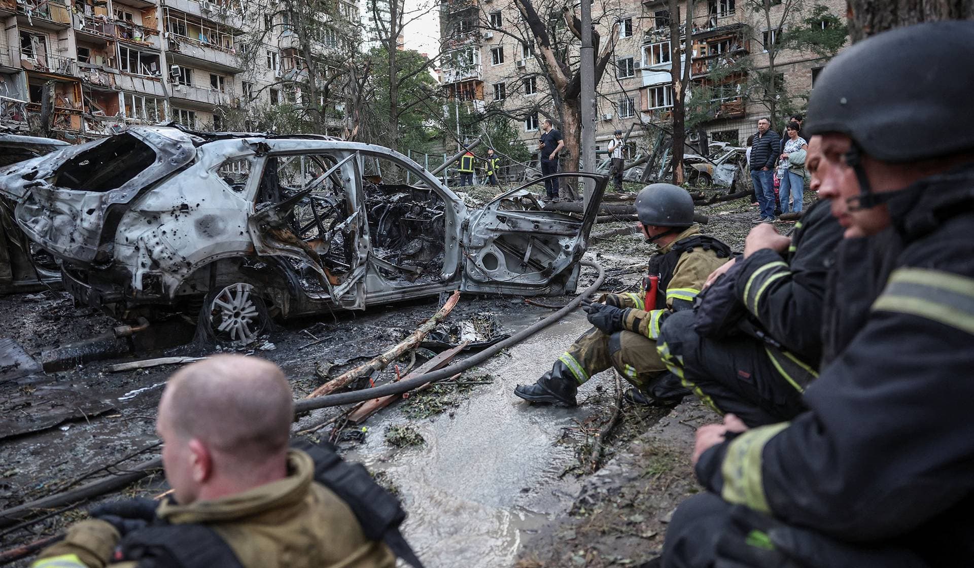 Firefighters take a break as they work at a site of a Russian missile and drone strikes in Kyiv