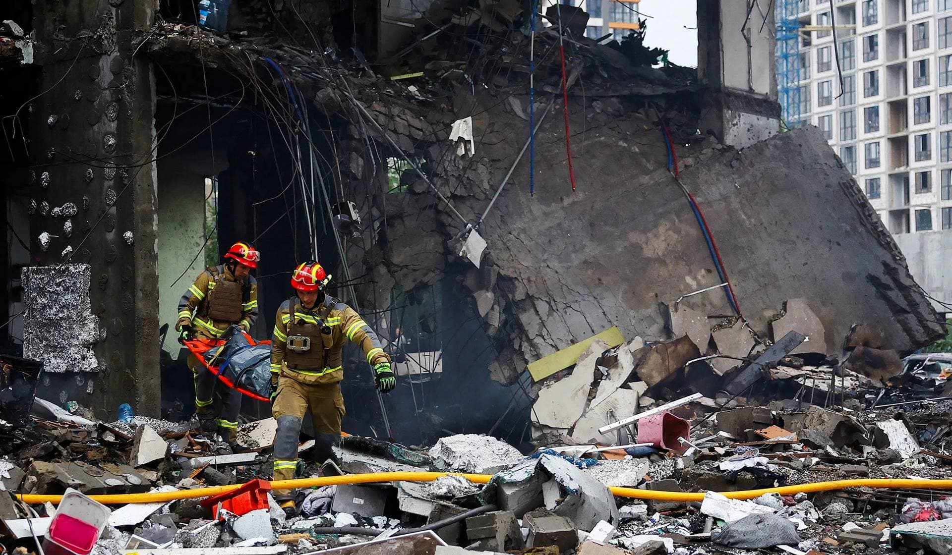 Rescuers carry a body at the site of an apartment building heavily damaged during Russian missile and drone strikes in Kyiv