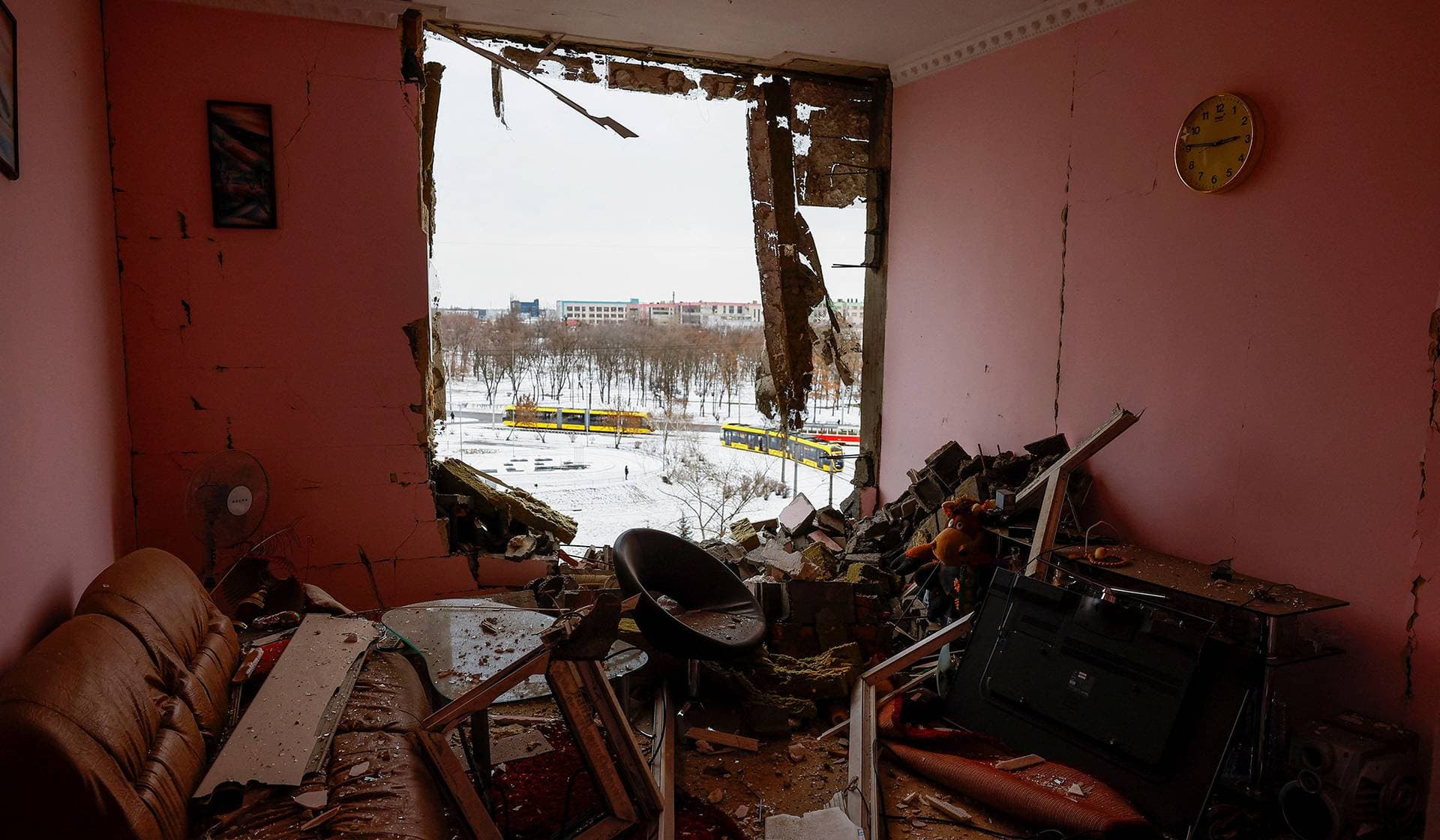 Debris scattered around a destroyed window opening, with trams seen in the background, at the site of an apartment building hit during Russian missile and drone strikes in Kyiv