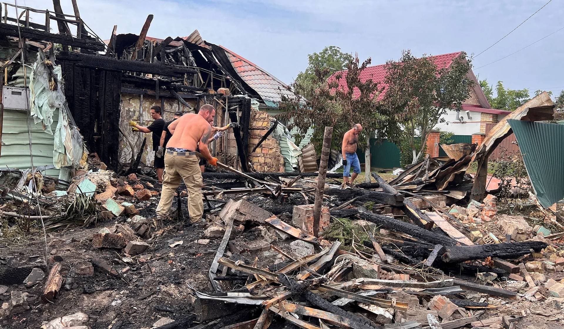 Local residents remove debris from buildings damaged by a Russian missile strike in the village of Tarasivka