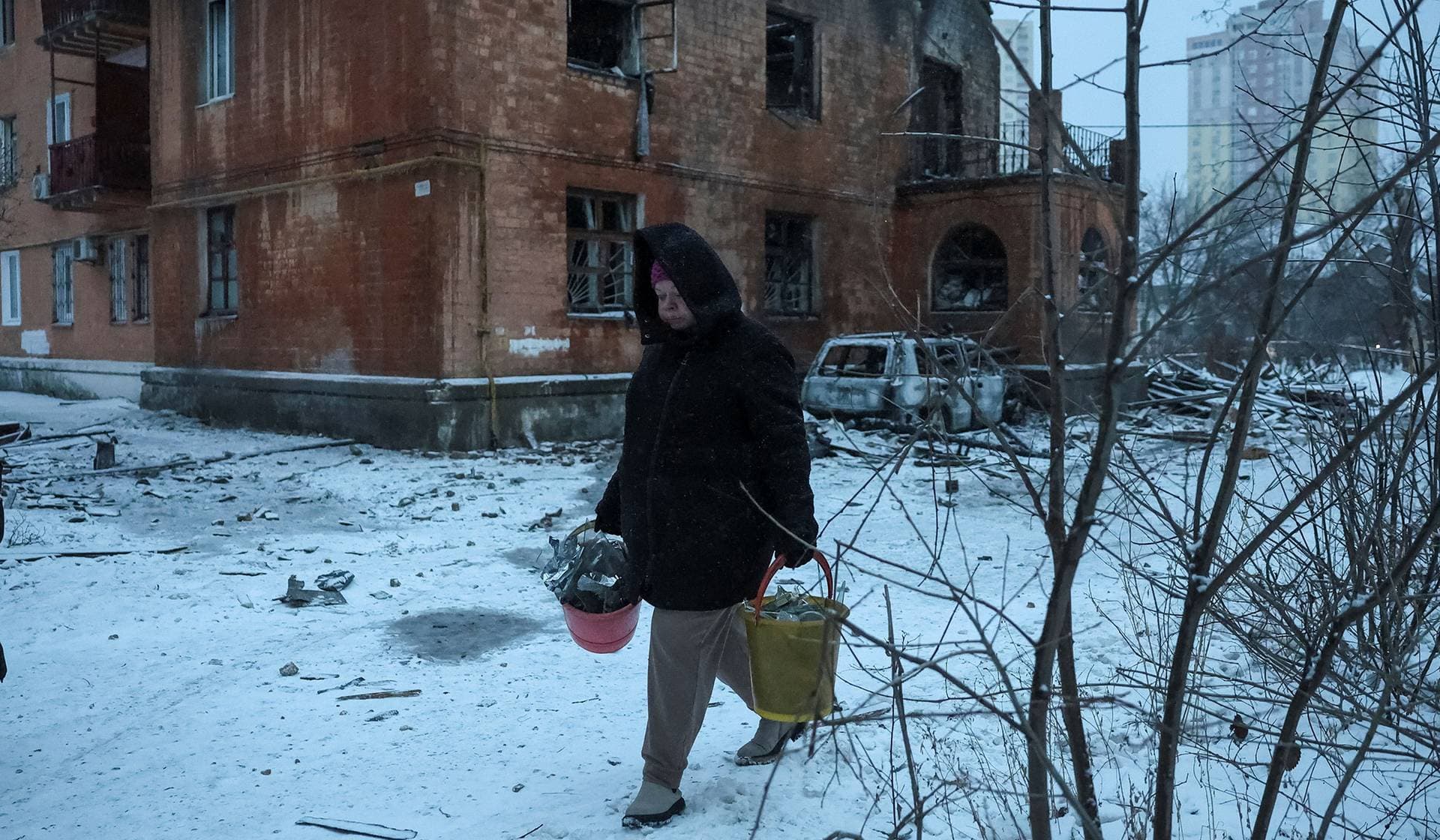 A resident removes debris at the site of an apartment building hit by a Russian drone strike in Kyiv