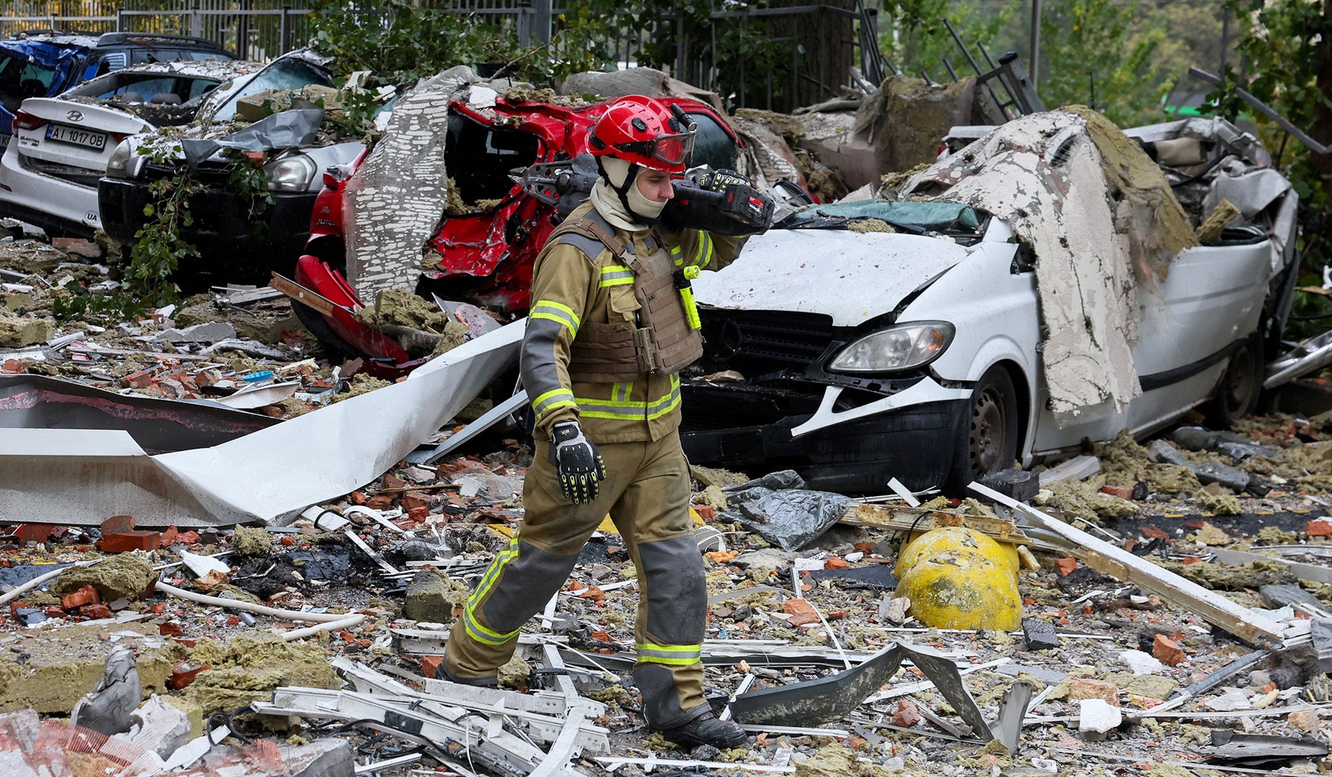 A first responder walks on debris at the site of an apartment building damaged during a Russian drone strike in Kyiv