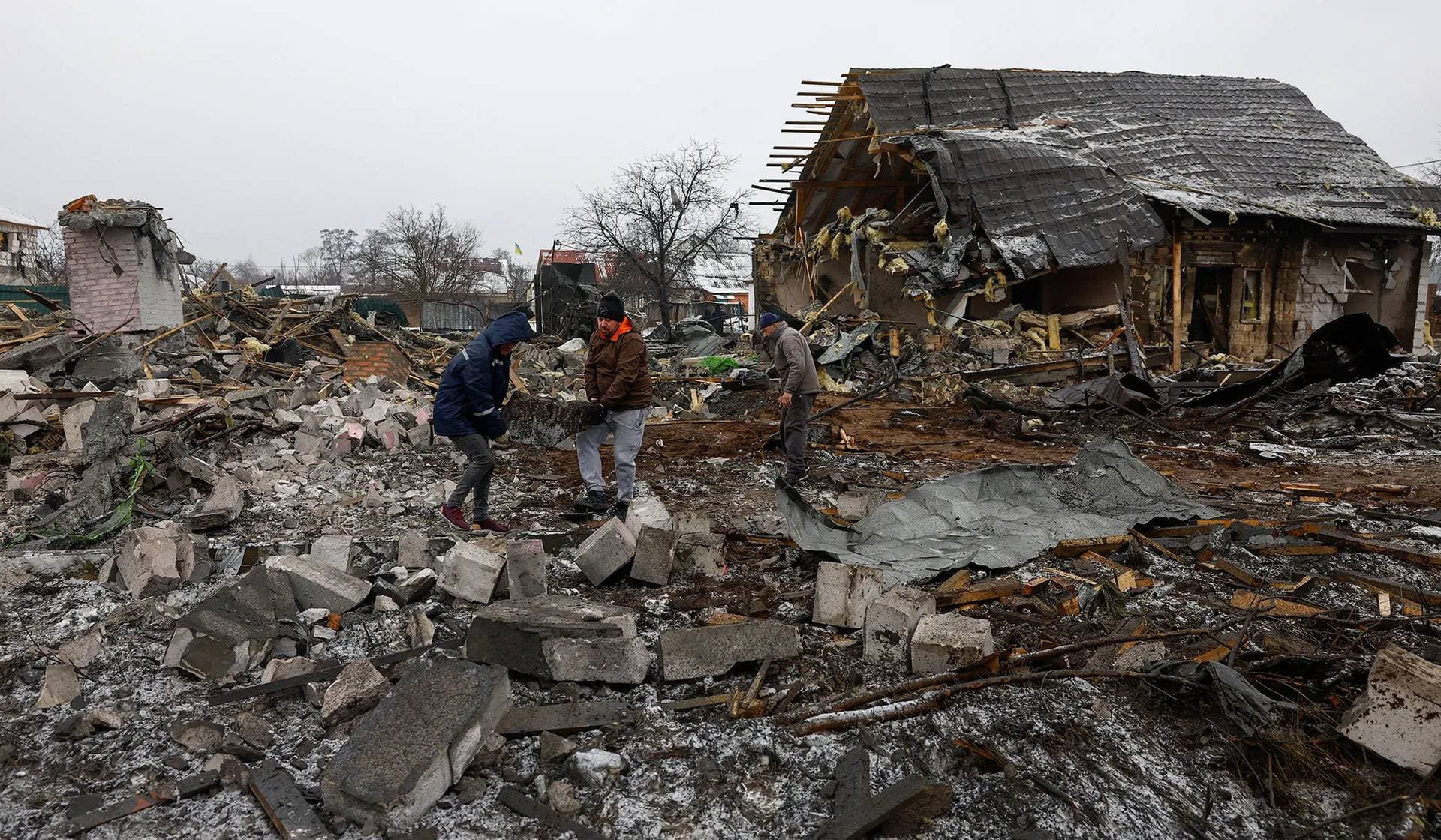 Local residents remove debris next to their neighbour's house, heavily damaged by a Russian missile strike, in Kyiv
