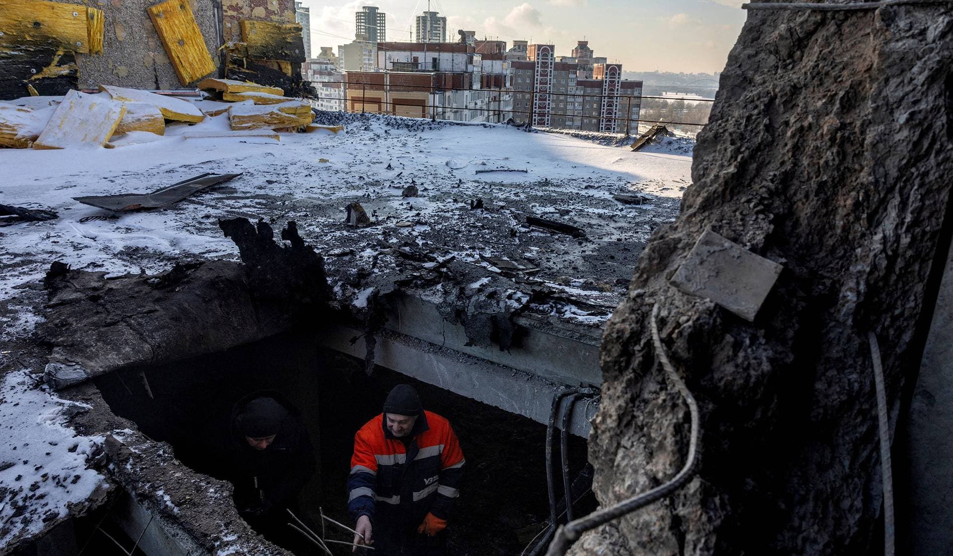 A resident shows a journalist where a Russian drone struck the roof of an apartment building, depriving its residents of water, heat, and electricity in Kyiv