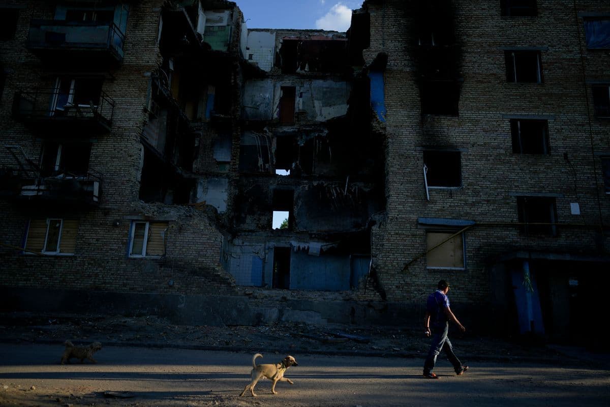 A man walks with his dog near a building destroyed by attacks in Gorenka